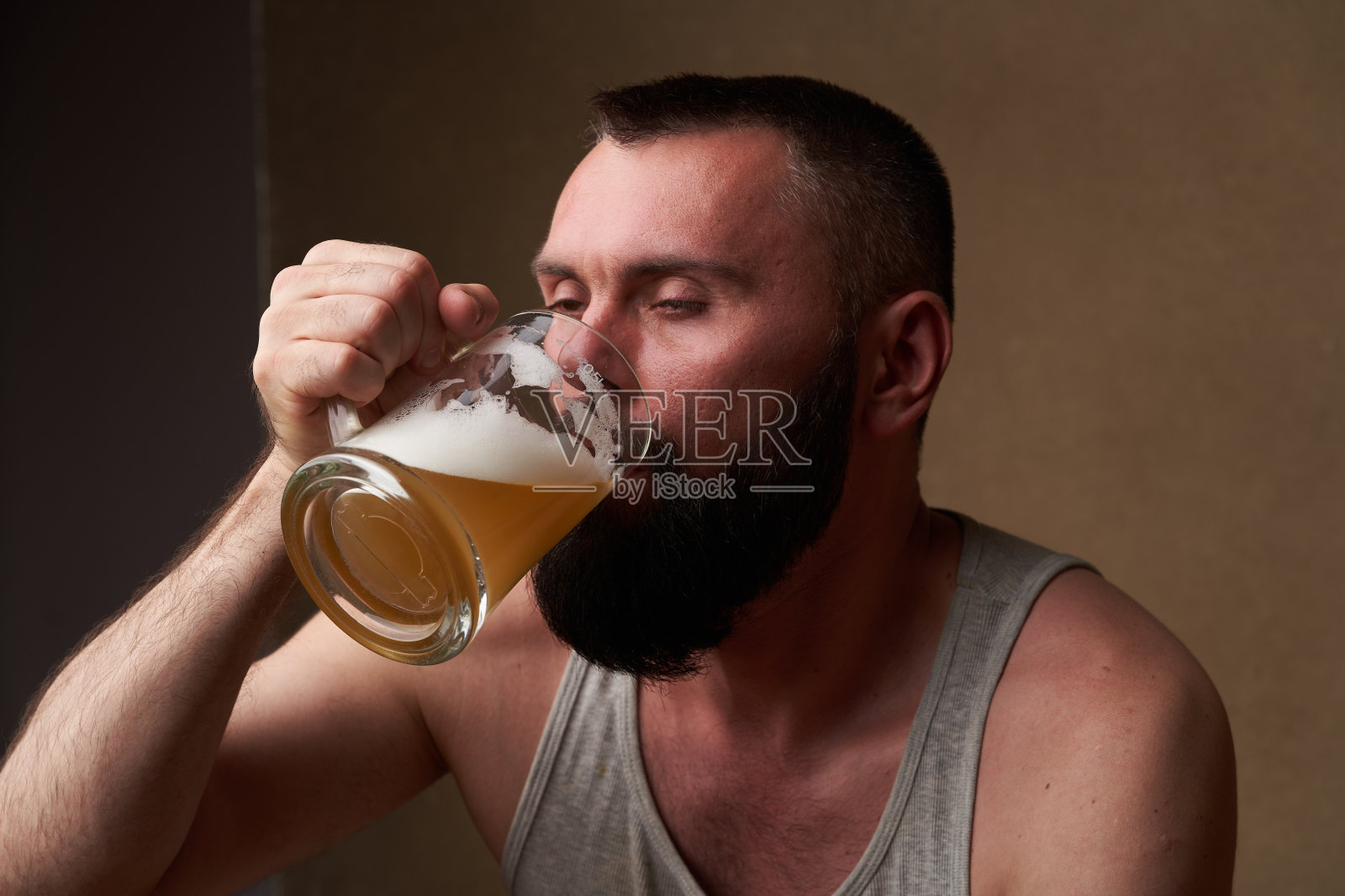 一个留着胡子的英俊男子的肖像，手里拿着一大杯啤酒照片摄影图片