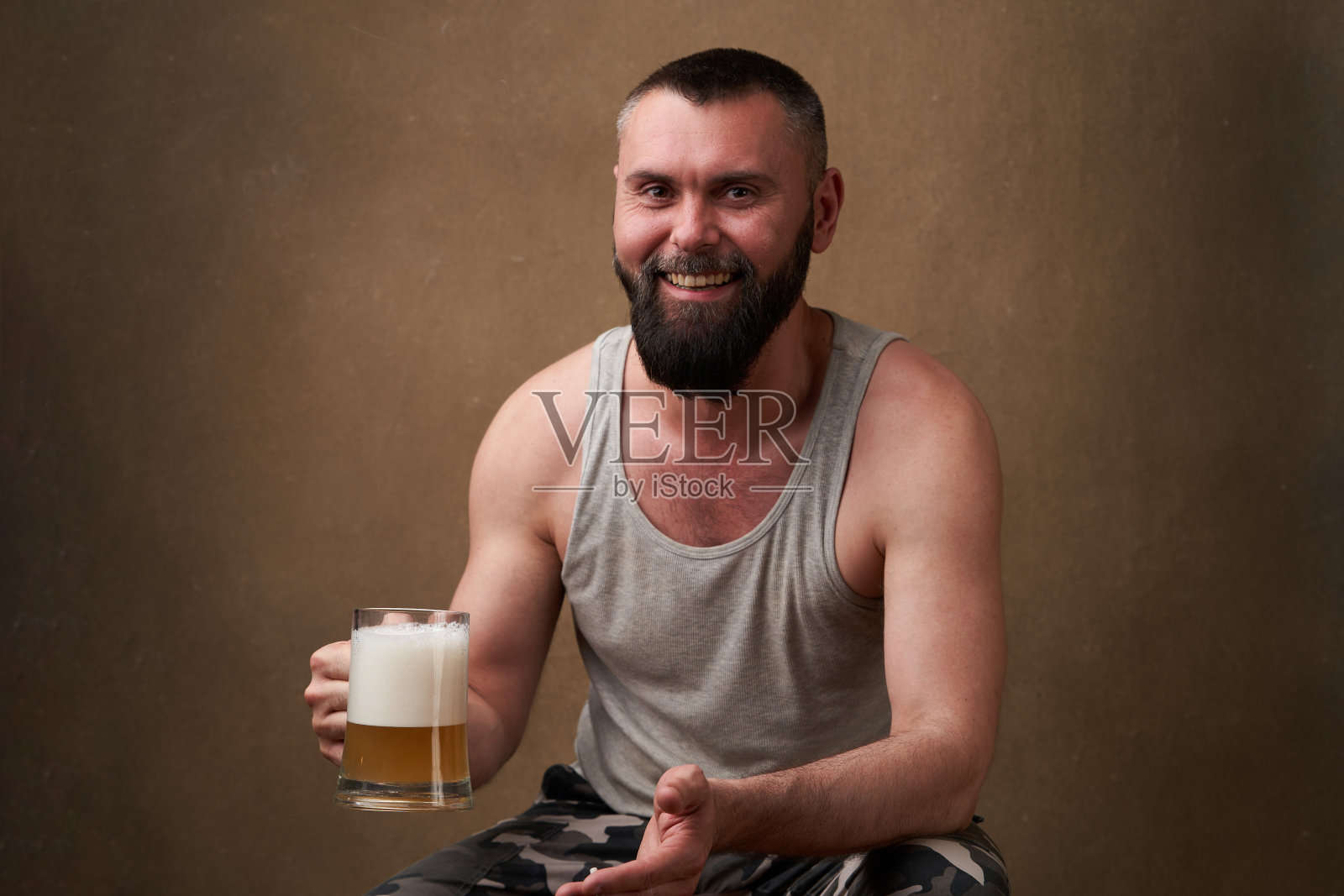 一个留着胡子的英俊男子的肖像，手里拿着一大杯啤酒照片摄影图片