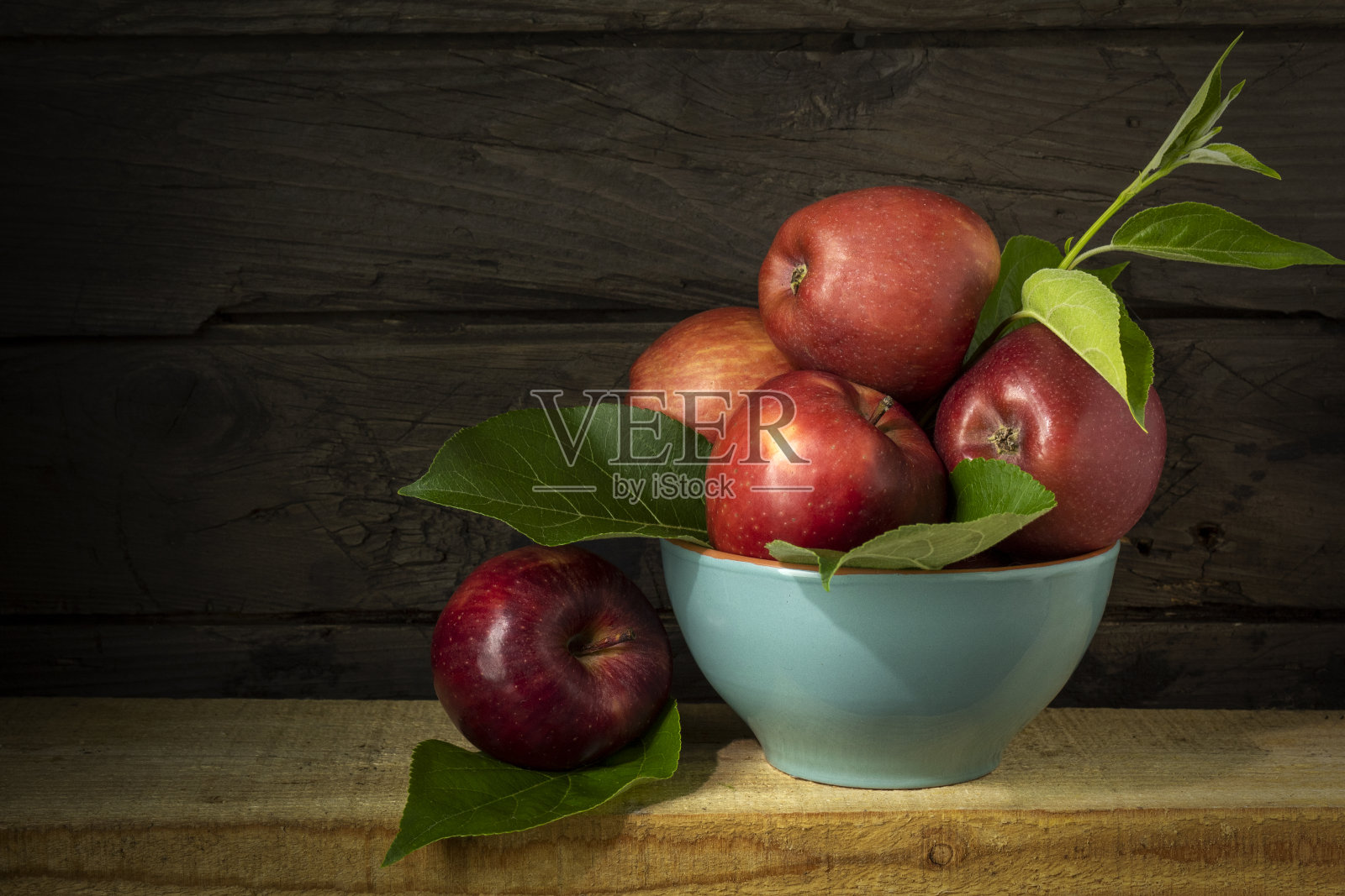 静物生活与蓝色碗成熟的苹果在木背景照片摄影图片