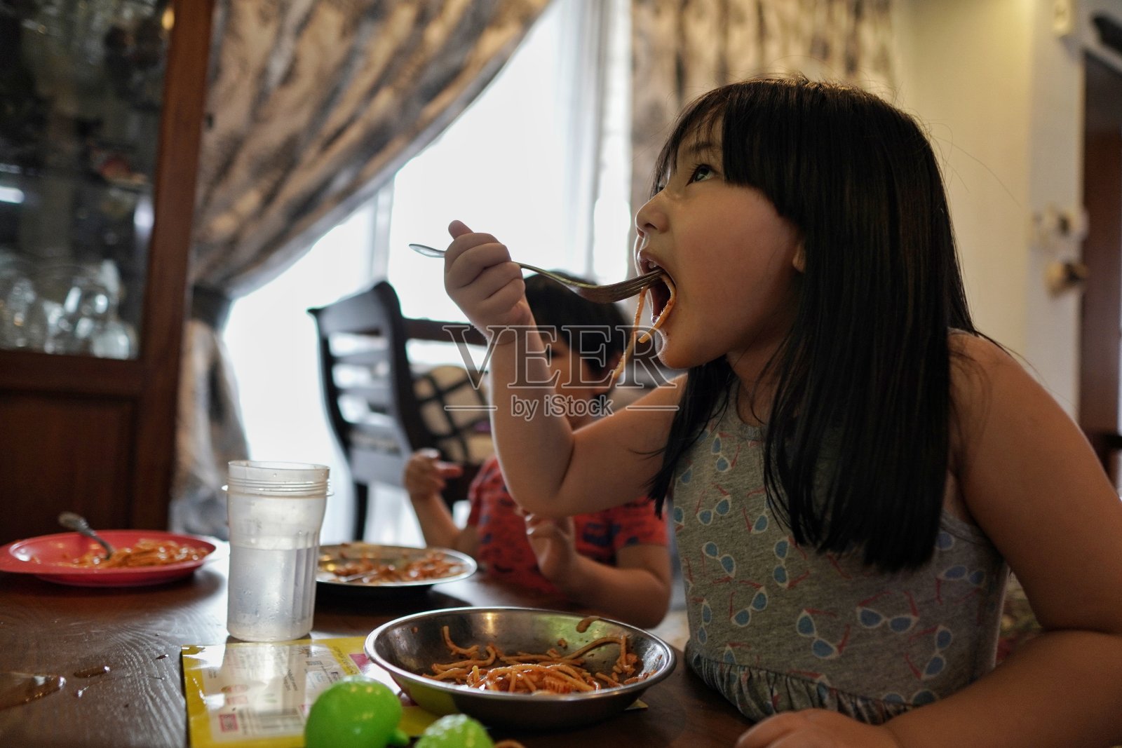 孩子在客厅看电视的时候吃意大利面照片摄影图片