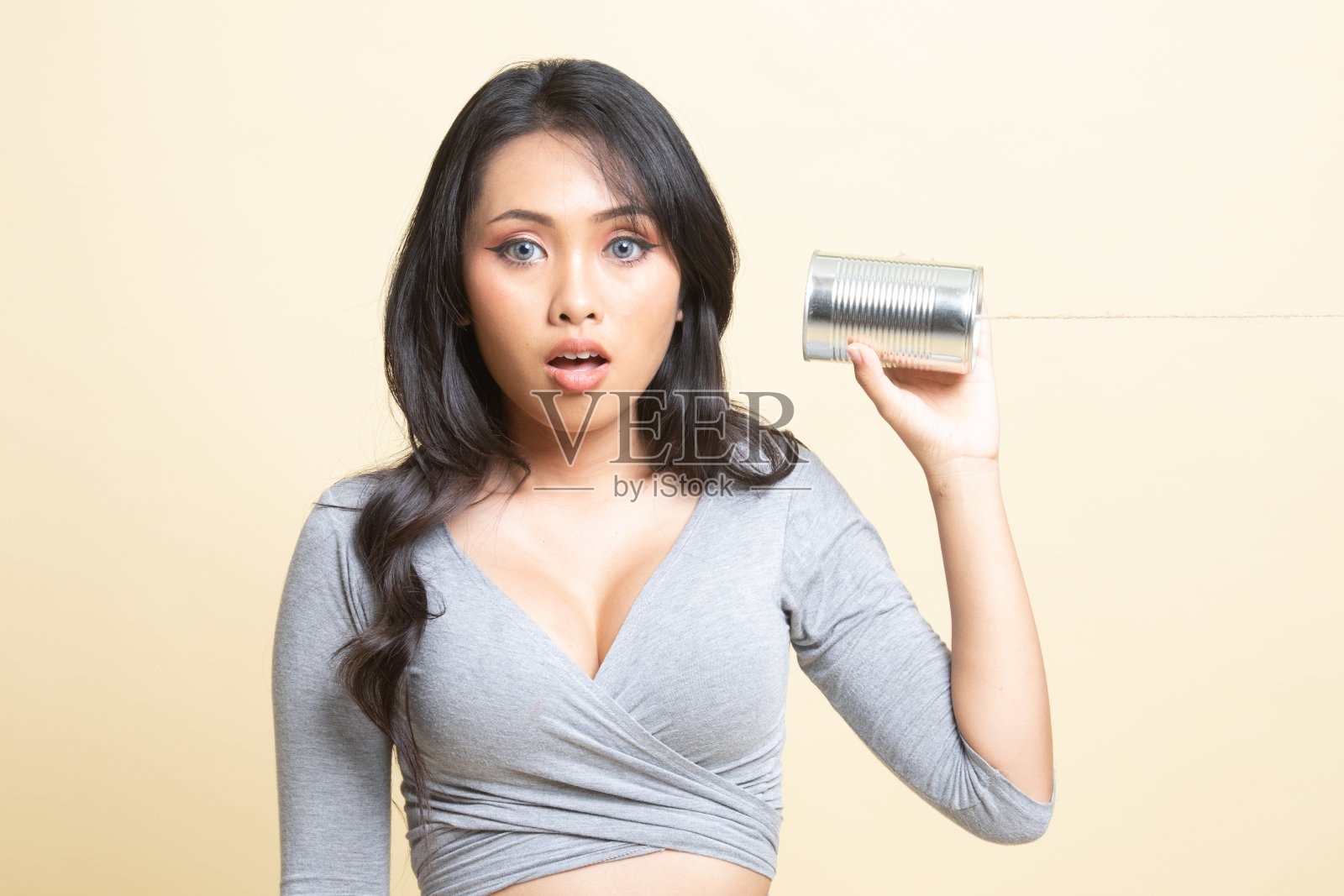 惊讶的年轻亚洲女子与锡罐电话。照片摄影图片