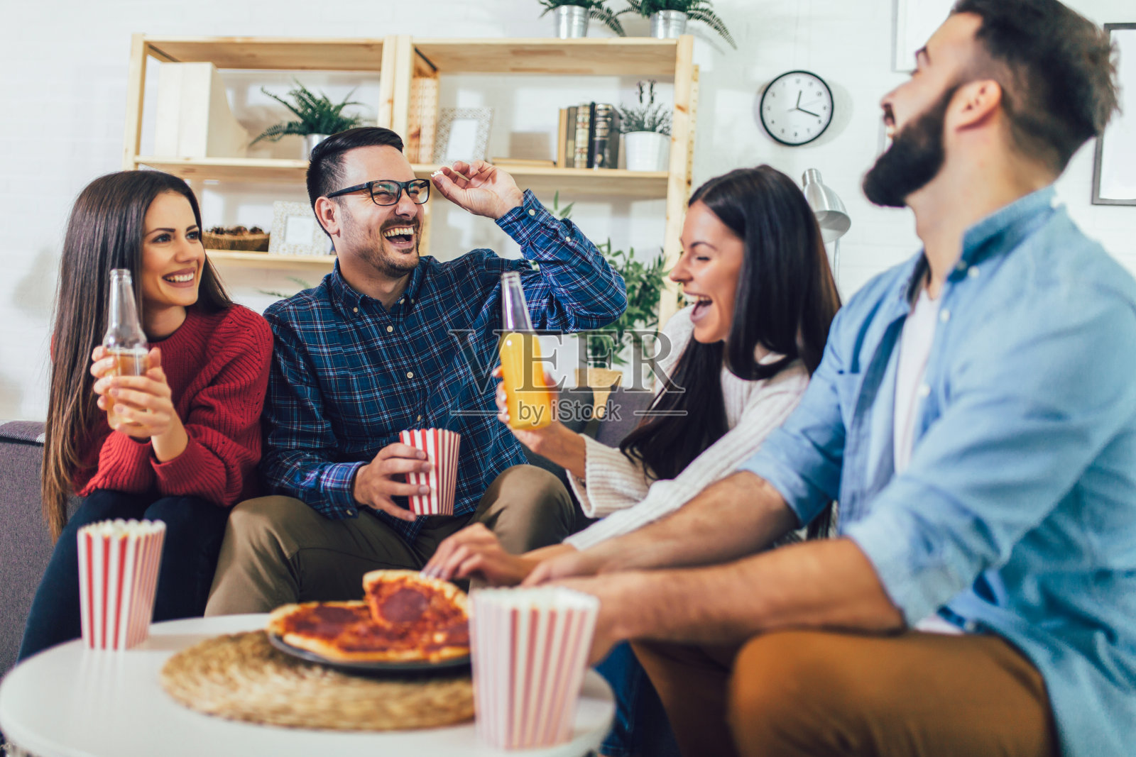 一群年轻的朋友在家里吃披萨。年轻人在一起玩。照片摄影图片