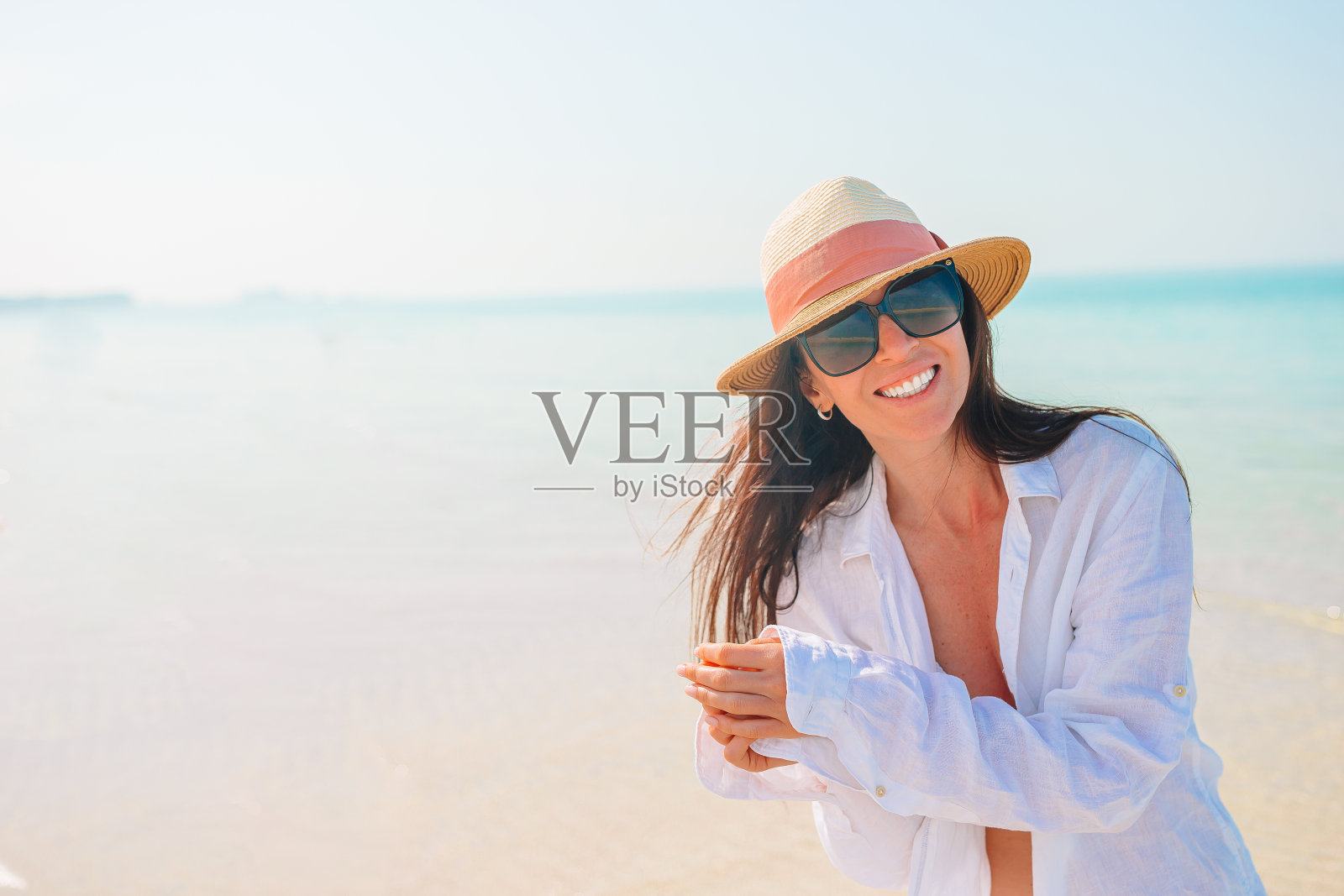 一个女人躺在沙滩上享受暑假，看着大海照片摄影图片