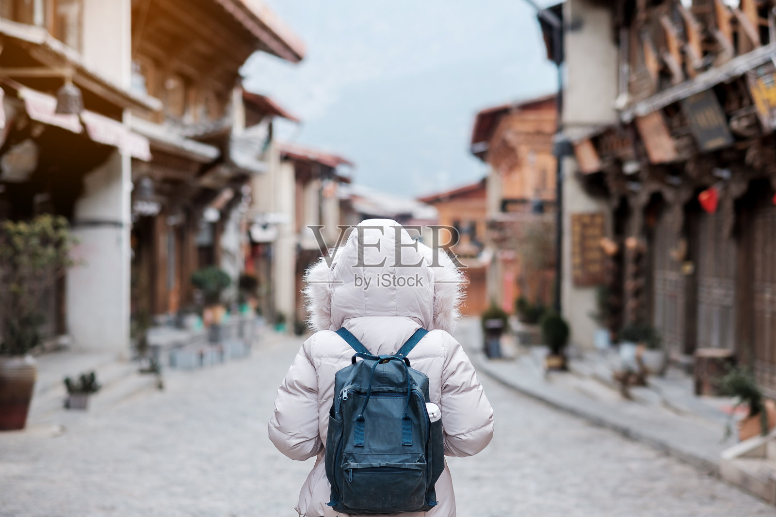 年轻女子旅行者与毛衣旅行在独克宗古镇，位于中甸市(香格里拉)。地标和受欢迎的旅游景点。中国云南。亚洲和独自旅行的概念照片摄影图片