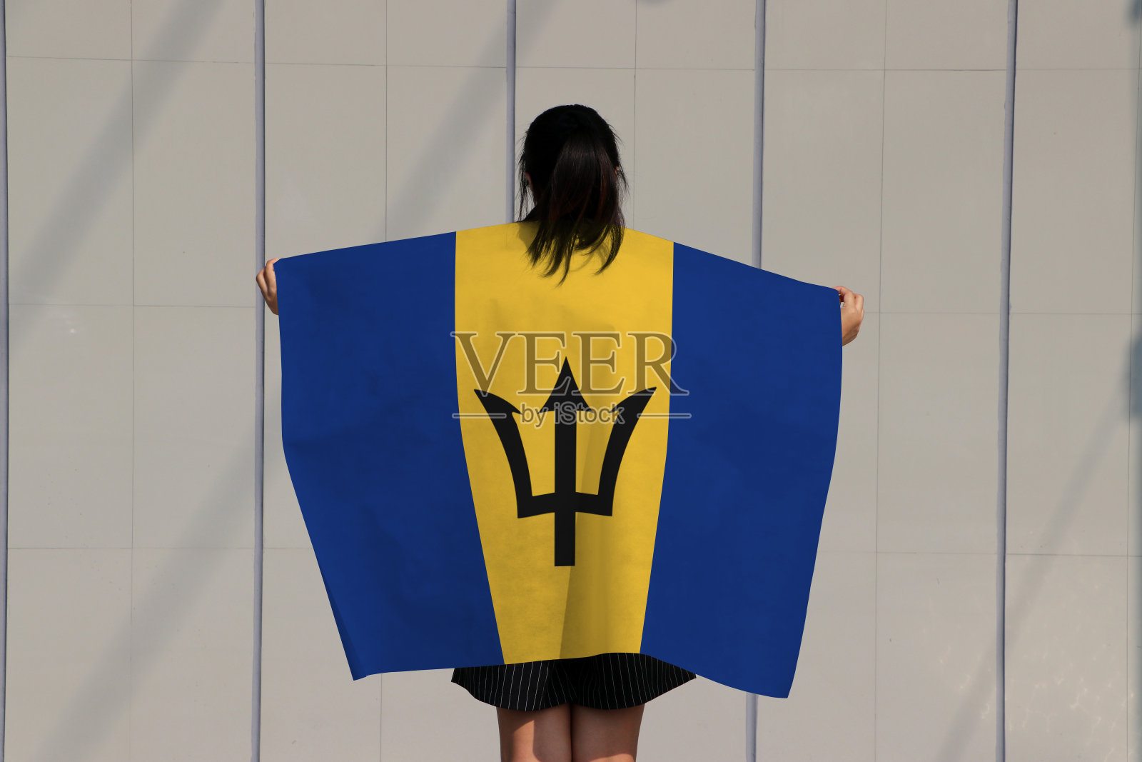 一名妇女肩上扛着巴巴多斯旗。照片摄影图片