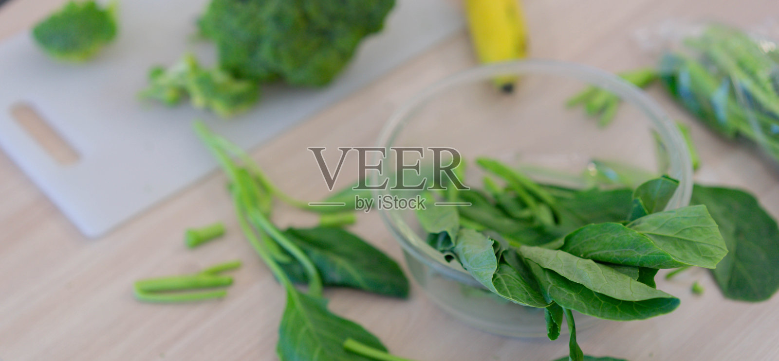 近距离在碗里的甘蓝菜叶子在厨房的桌子上，西兰花和香蕉在切菜板上准备素食健康的生活理念照片摄影图片