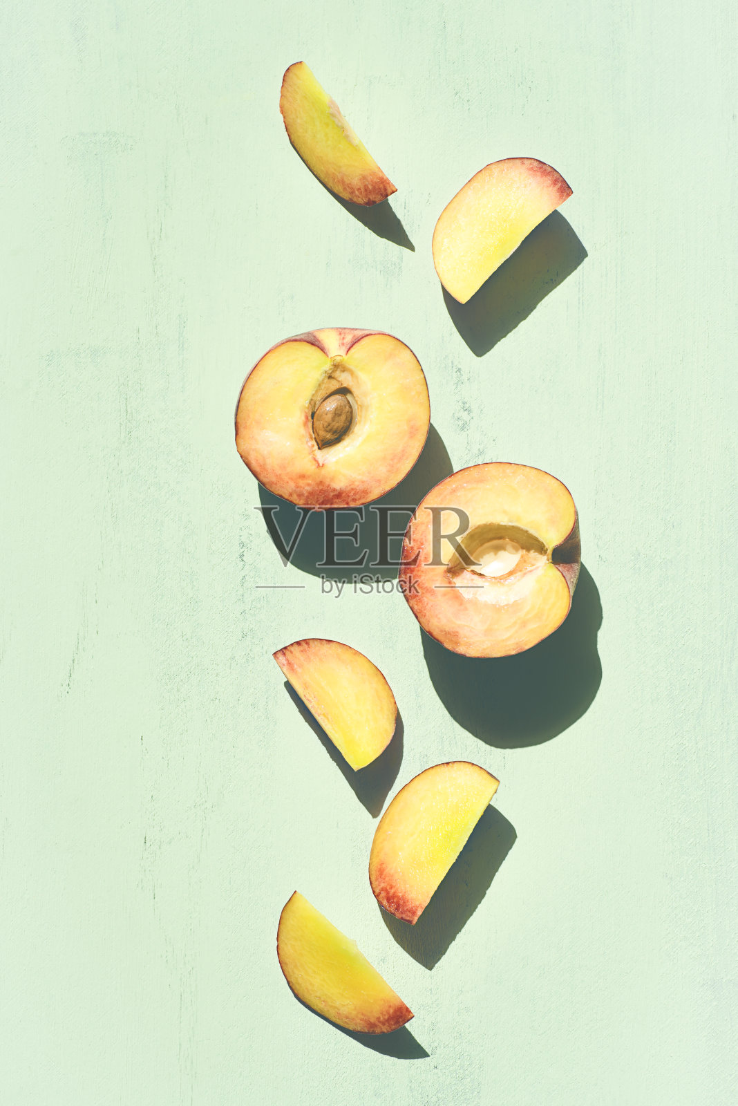 切好的桃子片在绿色薄荷的背景下有清晰的阴影。夏天的水果照片摄影图片