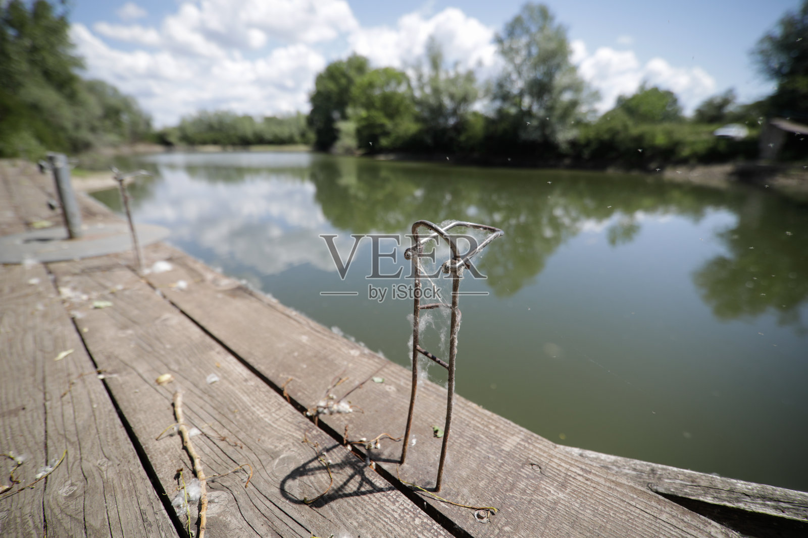 浅景深(选择性聚焦)的图像与一个旧的和未使用的金属支持的鱼竿在一个木制码头。照片摄影图片