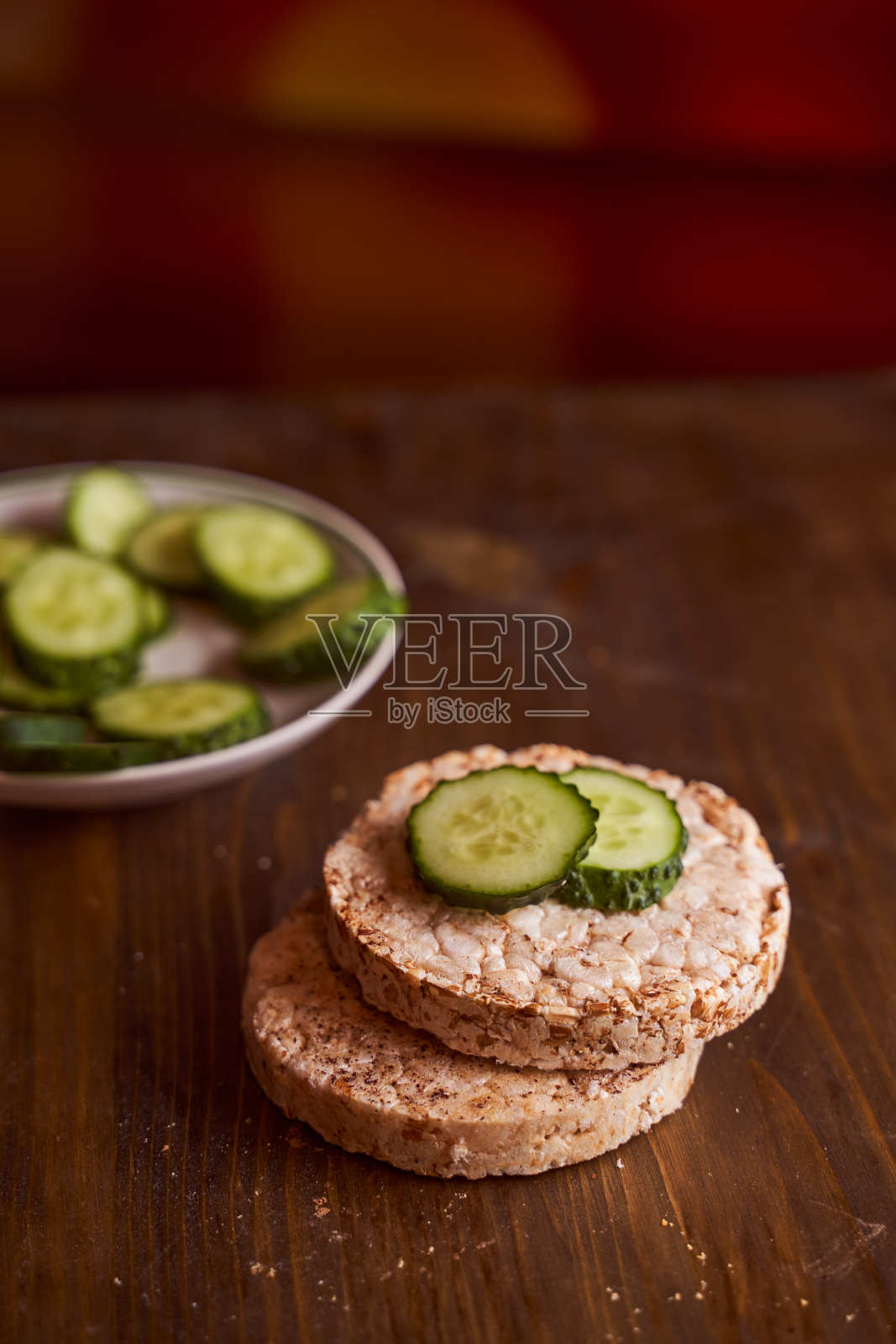 圆形的荞麦面包，上面有两根新鲜的黄瓜，背景是棕色的照片摄影图片