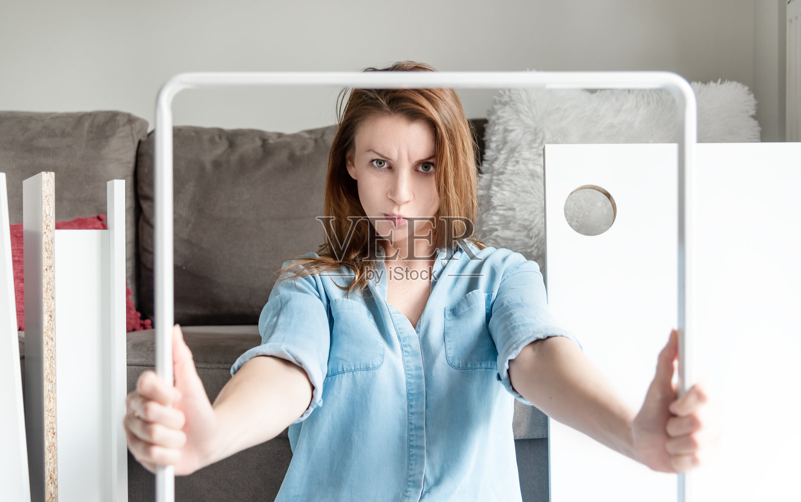 生气的女人看着扔家具的方形部分。Diy家具组装概念照片摄影图片