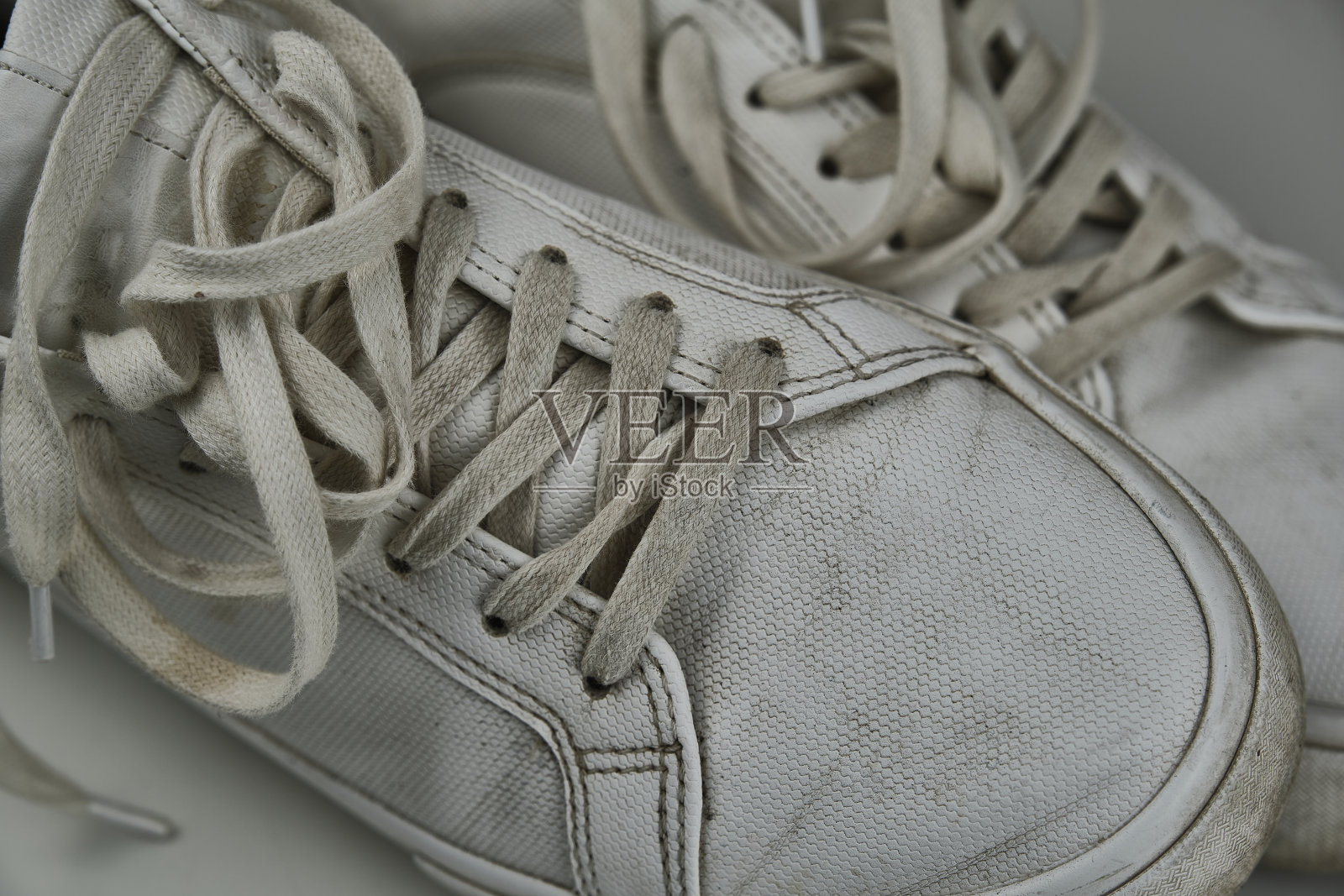 肮脏的，用过的，沾满泥巴的，白色的脏鞋子，在白色的脏地板上照片摄影图片