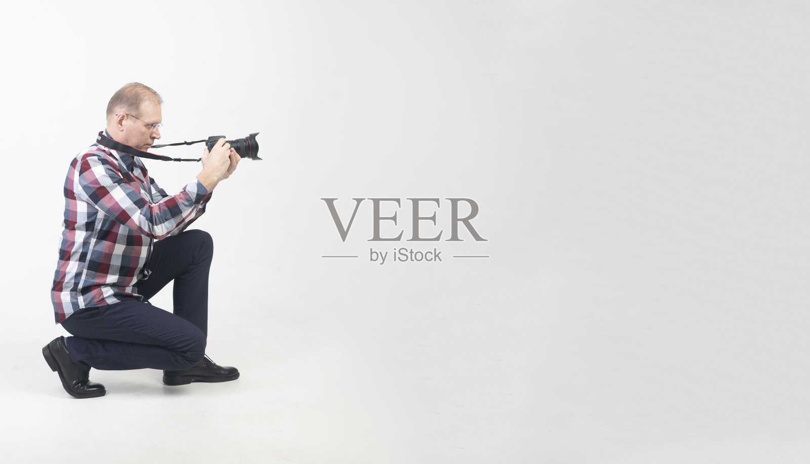 一个中年或摄影师白人男子在白色的背景。手里拿着相机的男人正在拍照。横幅照片摄影图片