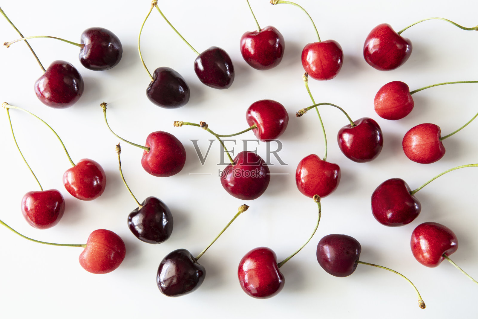 鲜红的樱桃散落在白色的背景上照片摄影图片
