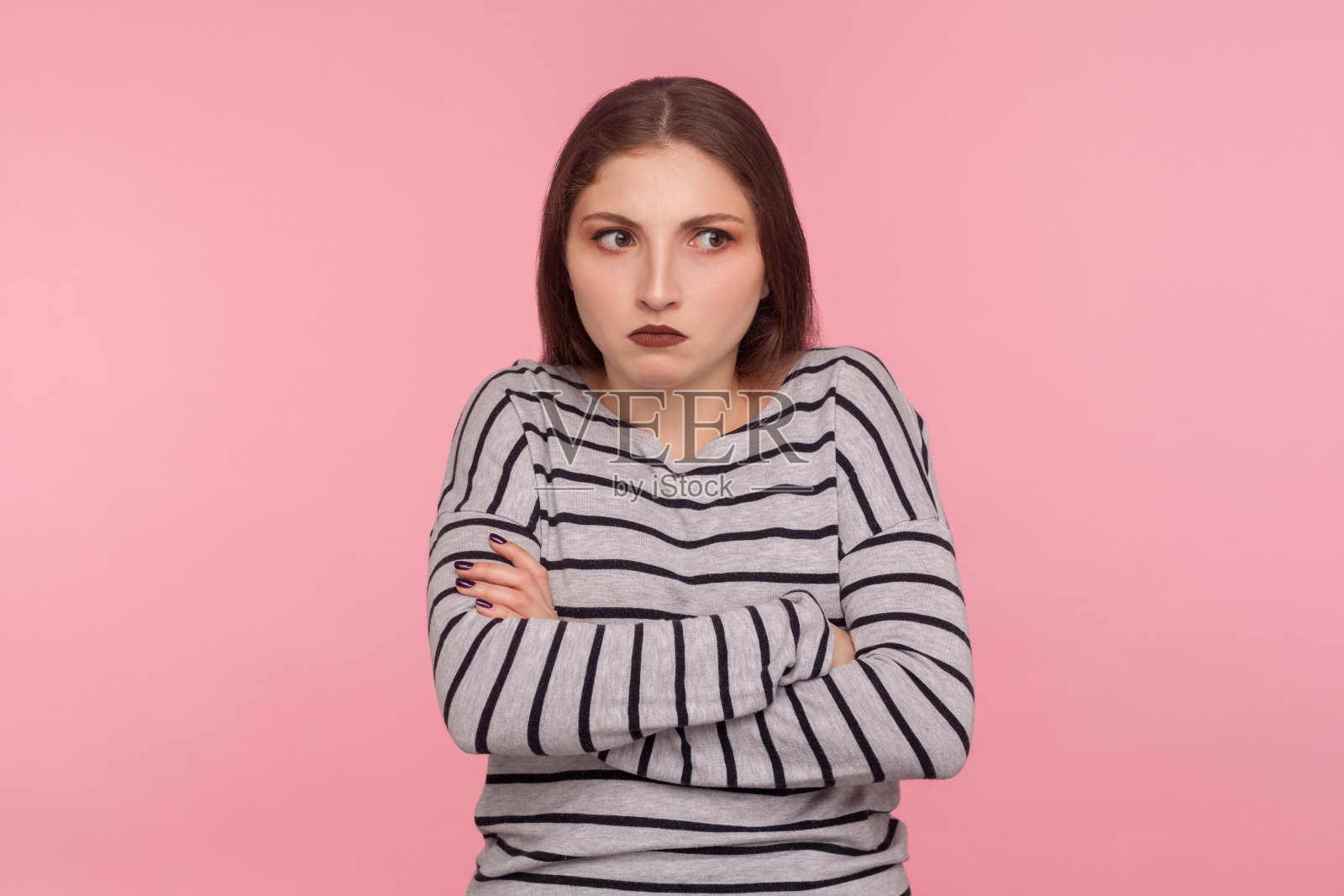 肖像困惑周到的女人在条纹运动衫站在交叉的双手，思考强烈照片摄影图片