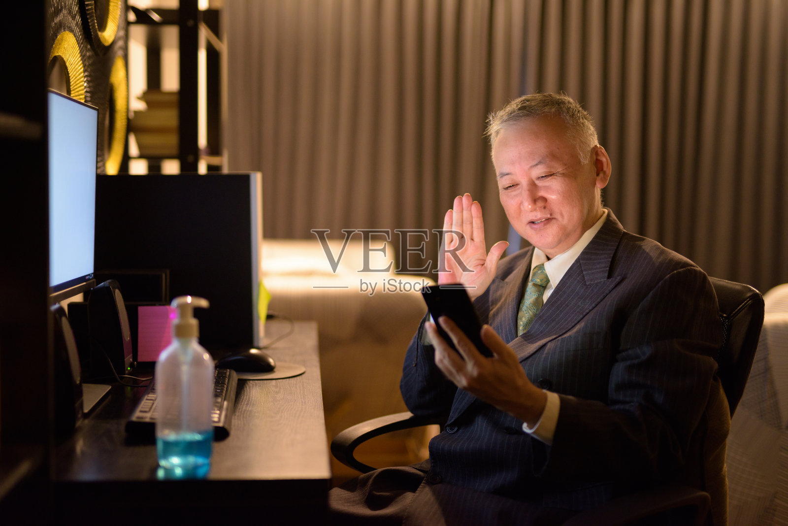 快乐成熟的日本商人在深夜加班时用电话视频通话照片摄影图片