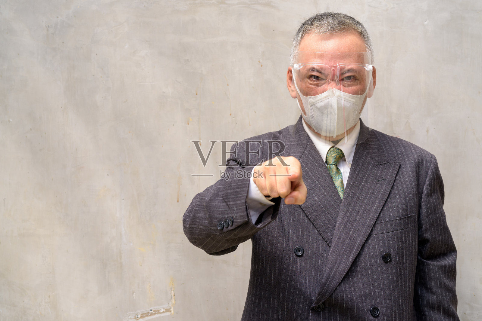 强调成熟的日本商人戴着面具和面罩指着相机照片摄影图片