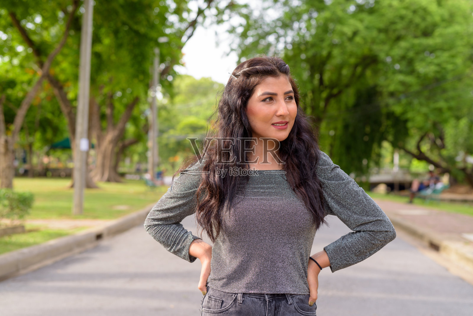 快乐的年轻漂亮的印度女人在公园的街道上思考照片摄影图片
