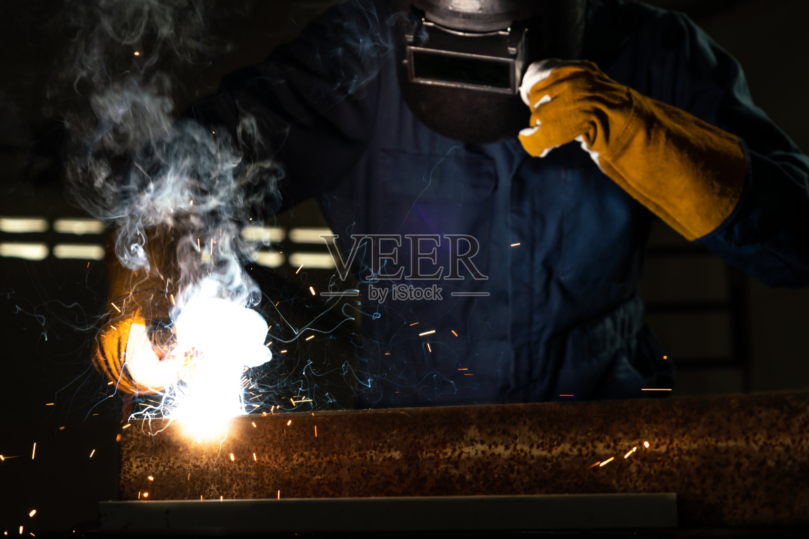 金属焊工在工厂使用电弧焊机焊接钢材时佩戴安全设备。金属制品制造和建筑维修服务，以手工技能劳动理念。照片摄影图片