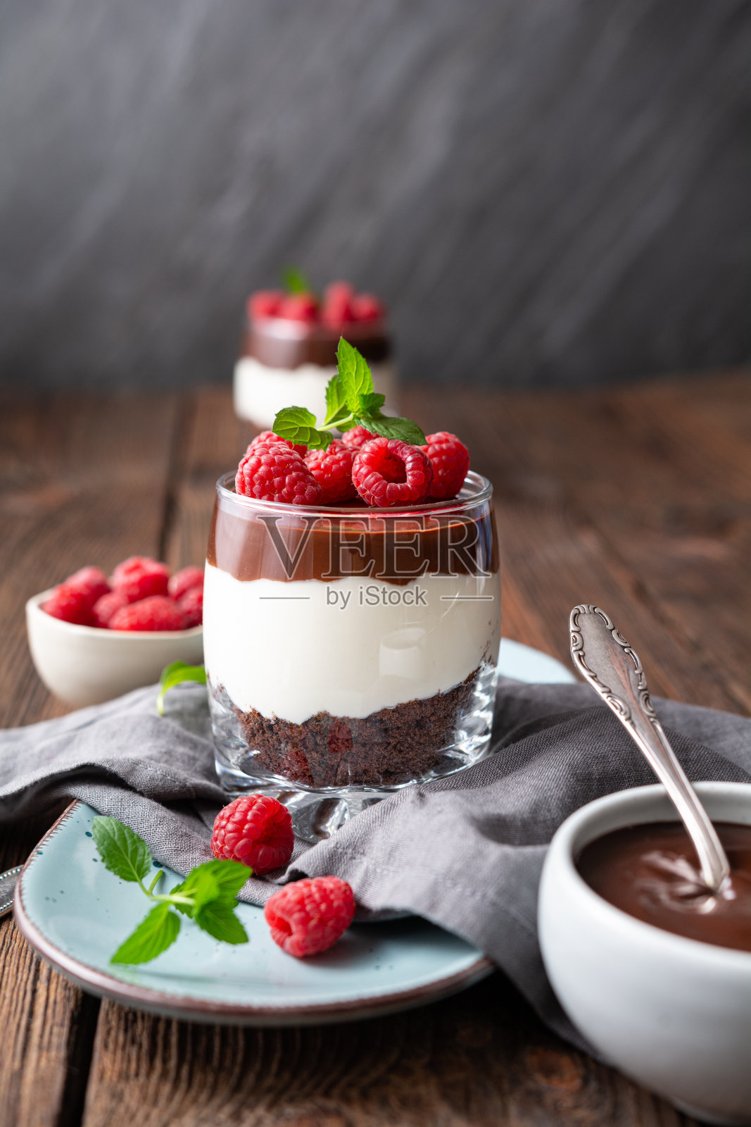 美味的分层甜点，奶油芝士，碎巧克力饼干，淋上甘纳许和新鲜的树莓照片摄影图片