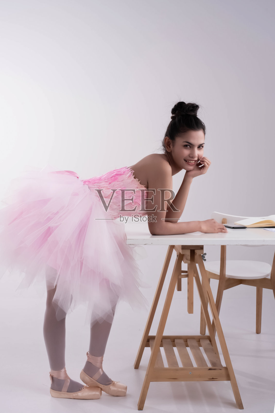 年轻美丽的女士穿着粉红色的芭蕾舞服，看着带着微笑的脸，肖像模特摆姿势照片摄影图片