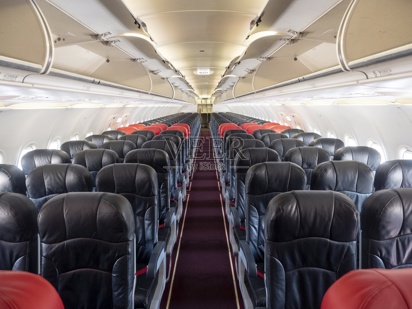 头等舱和经济舱的座位排。红色和黑色的座位。经济中突出红色溢价座位。照片摄影图片