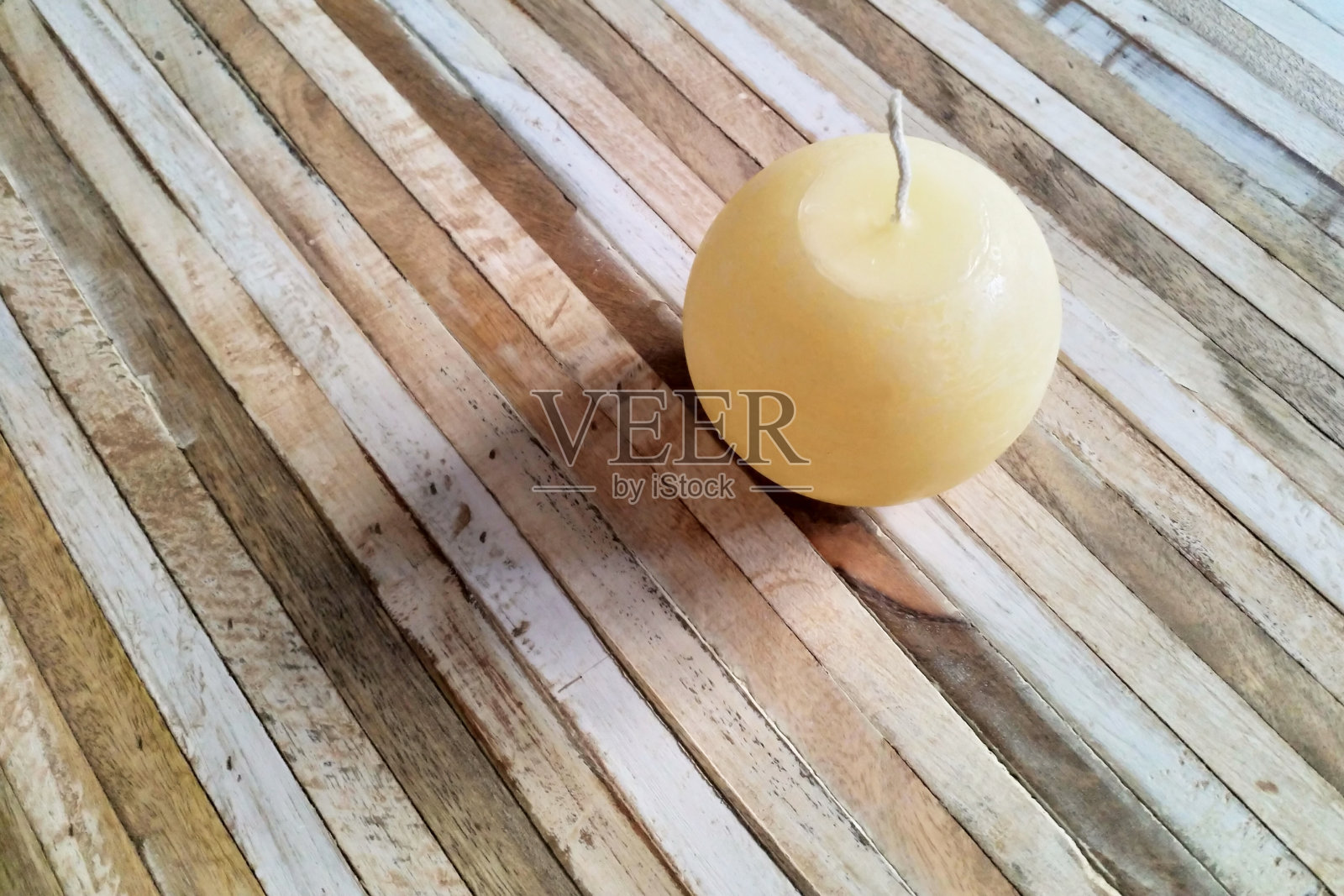 球形蜡烛斜放在小木头表面照片摄影图片