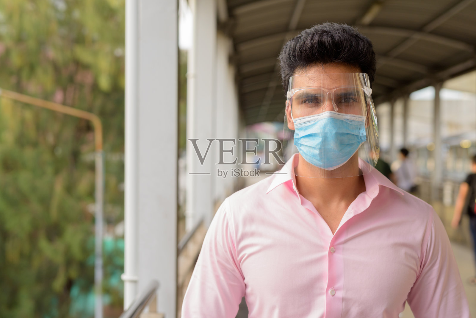 年轻的印度商人戴着面具和面罩站在人行桥上照片摄影图片