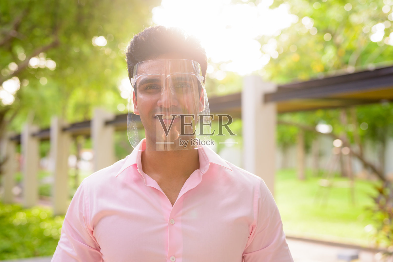 快乐的年轻印度商人戴着面罩在公园里微笑照片摄影图片