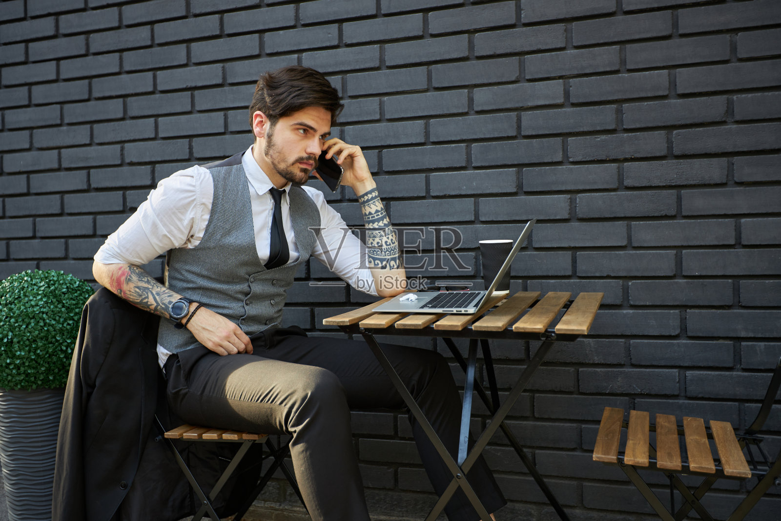 英俊的白人微笑商人坐在他的电脑上，穿着西装照片摄影图片