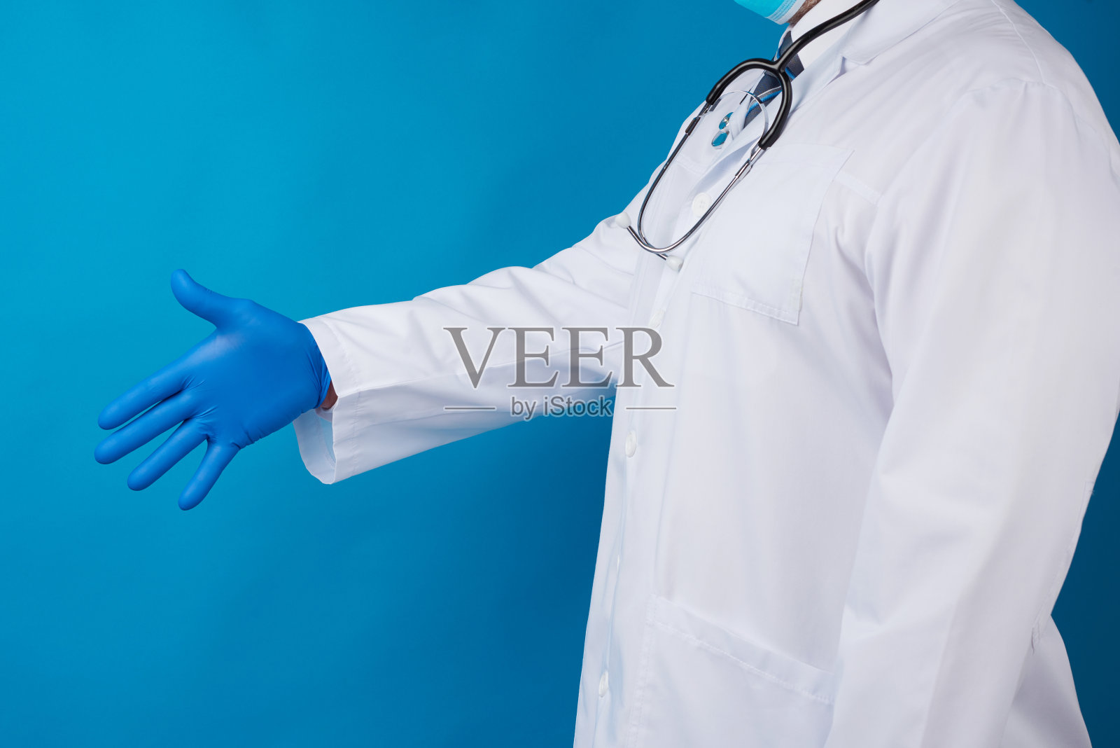 医生穿着一件有纽扣的白大褂，戴着蓝色乳胶手套，伸出手来照片摄影图片