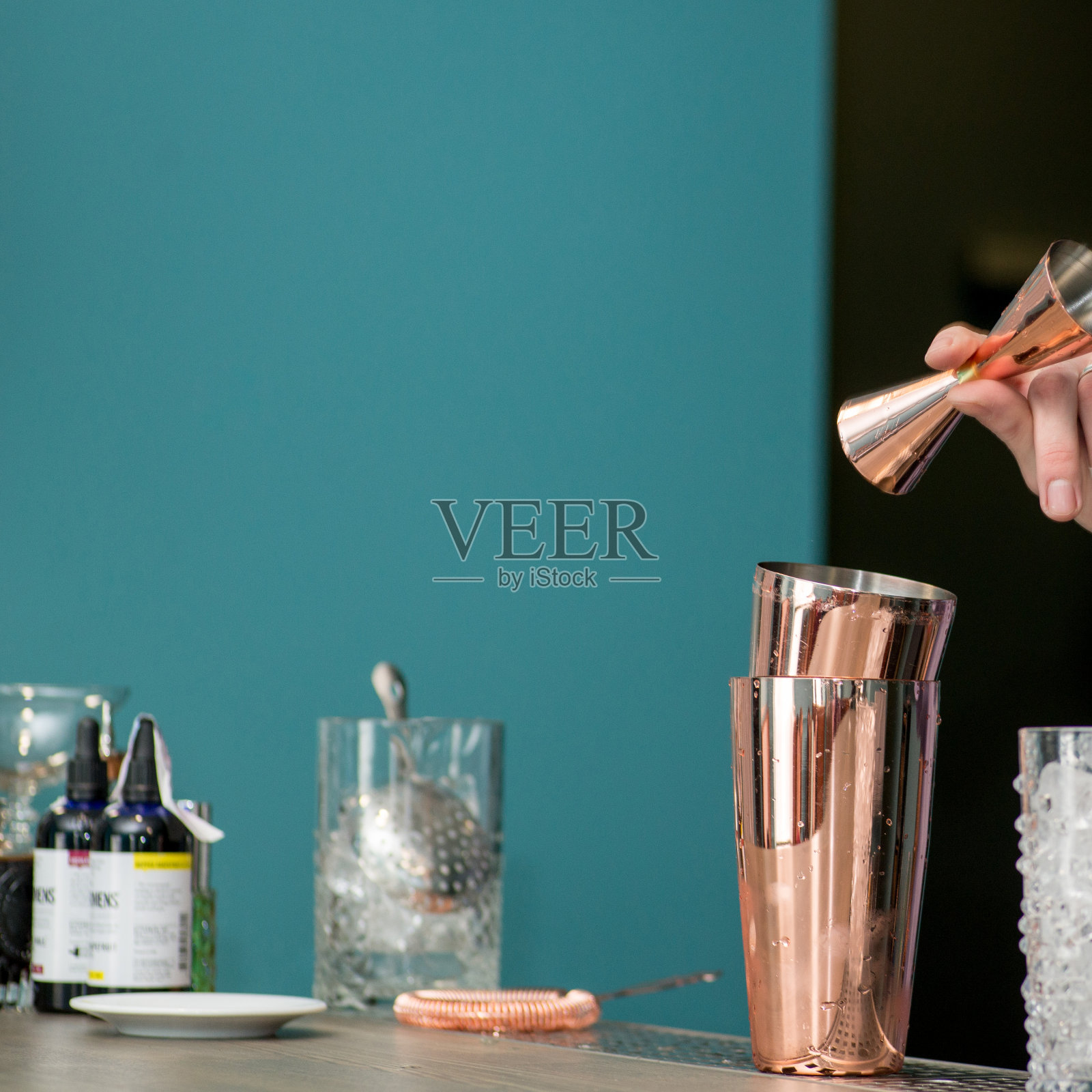 调酒师混合鸡尾酒在一个摇壶和倒它的背景与文字的地方。制作鸡尾酒。调酒术照片摄影图片