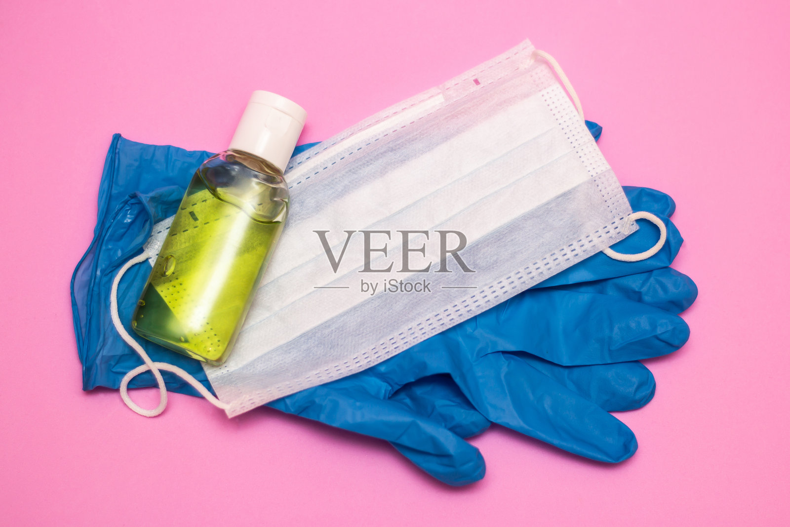 粉色背景上的手部消毒和白色面膜照片摄影图片