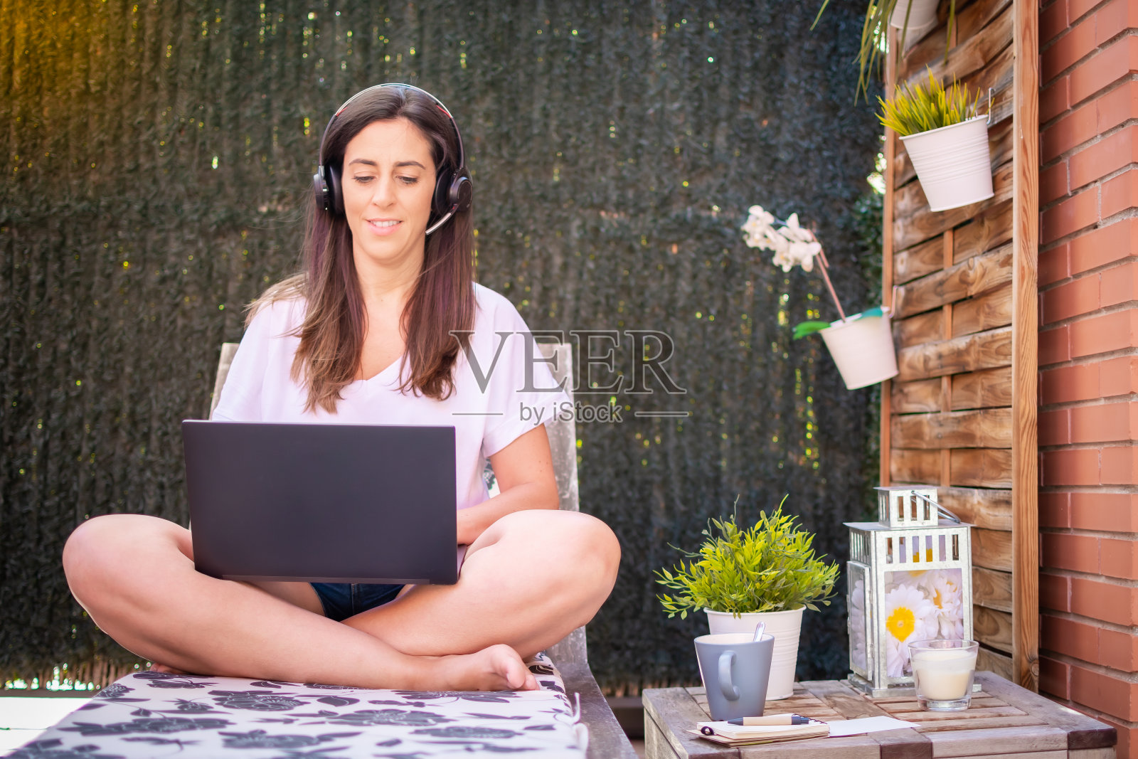 女性自由职业者，在笔记本电脑上写旅游博客。坐在花园里的躺椅上照片摄影图片