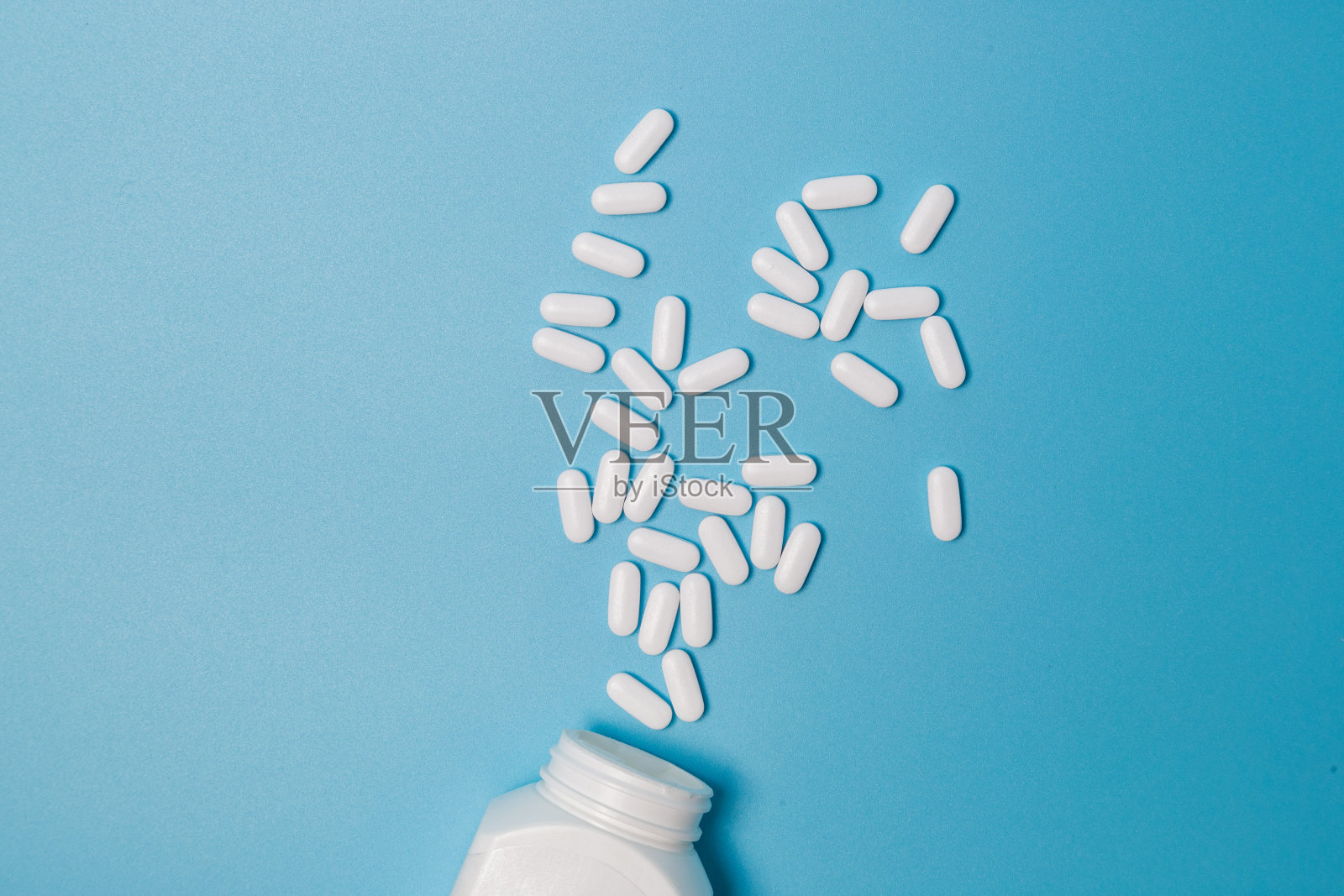 白色的药丸和药片从药瓶里溢出来。带有拷贝空间的宏自顶向下视图照片摄影图片