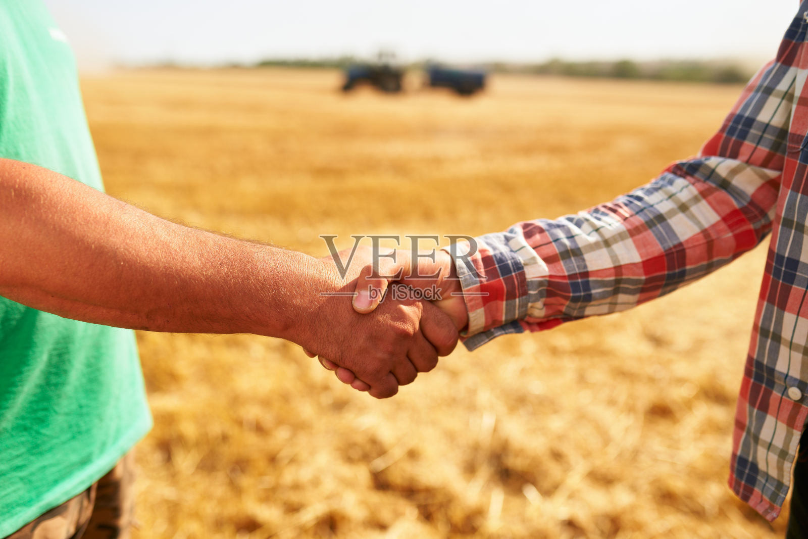 农夫和农学家在约定后握手站在麦田里。农业经营合同概念。联合收割机司机和牧场主握手后收获。谈判照片摄影图片