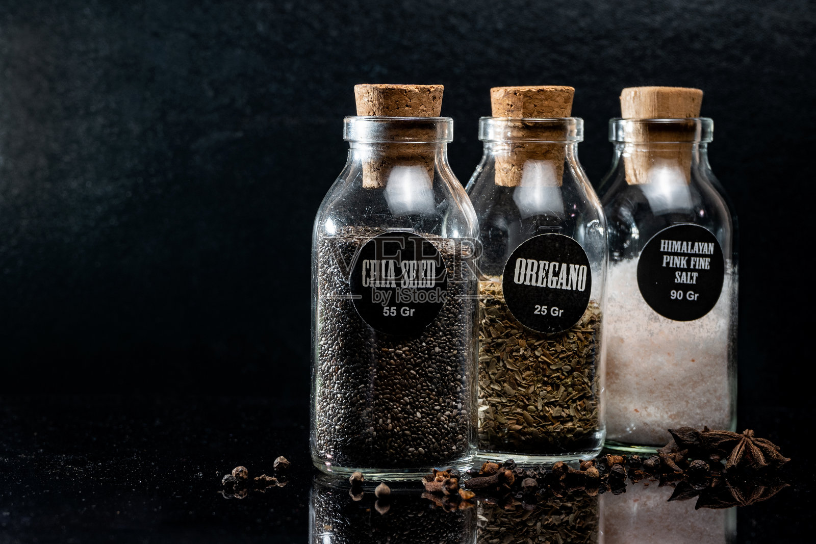 特写奇亚籽，牛至和喜马拉雅粉细盐在玻璃瓶与茴芹和丁香在黑暗的背景照片摄影图片
