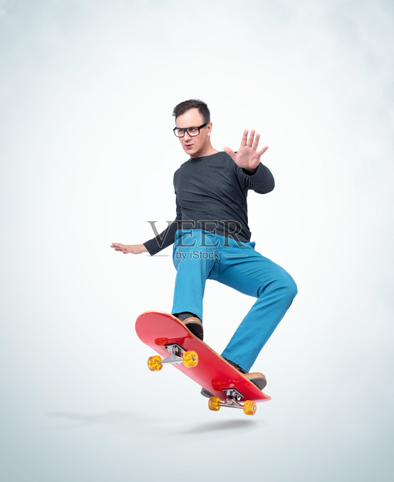 情绪化的男人穿着休闲的衣服在滑板上玩极端，孤立在光的背景。照片摄影图片