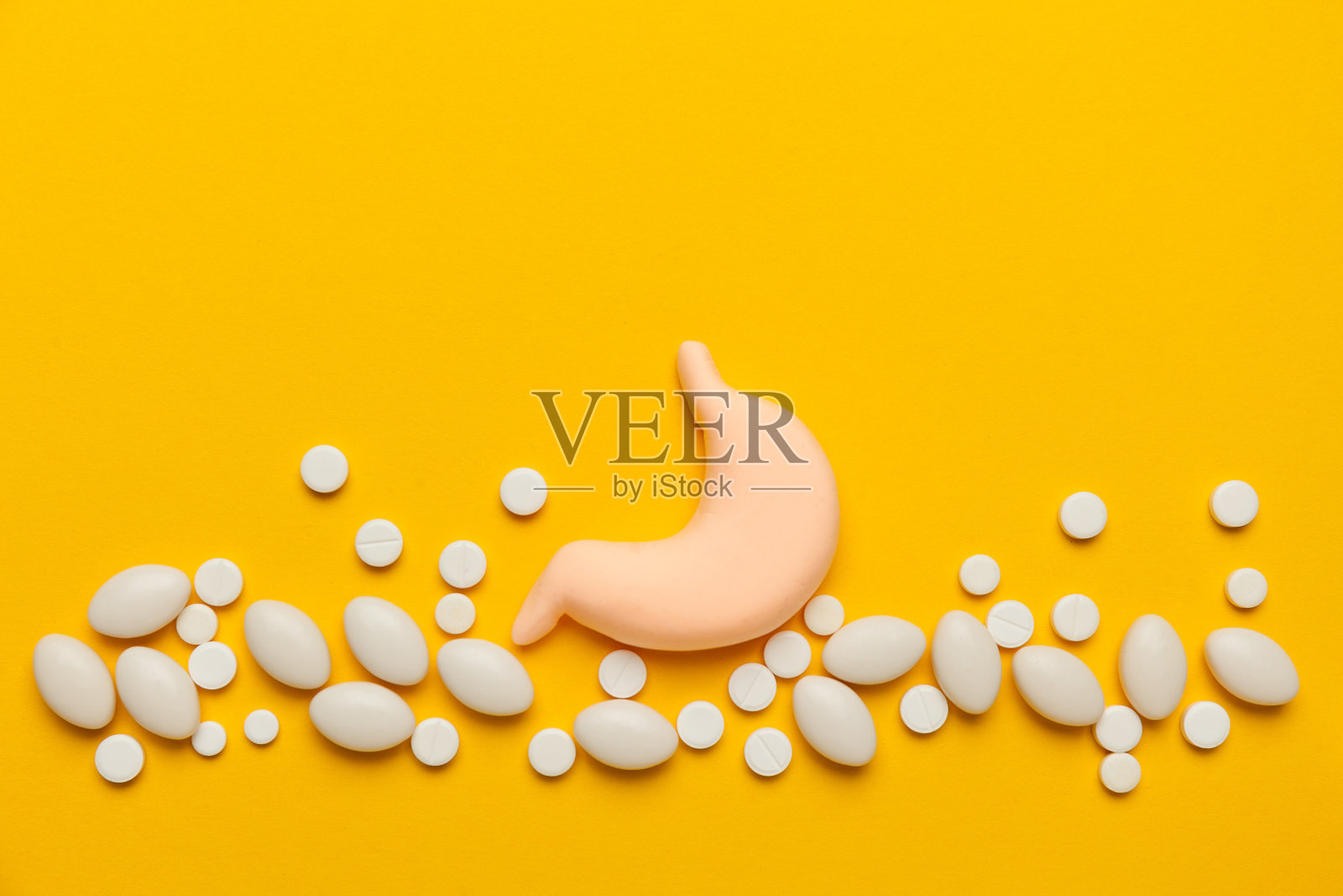 黄色背景上是人的胃。治疗疼痛和炎症。胃炎、烧心症状照片摄影图片