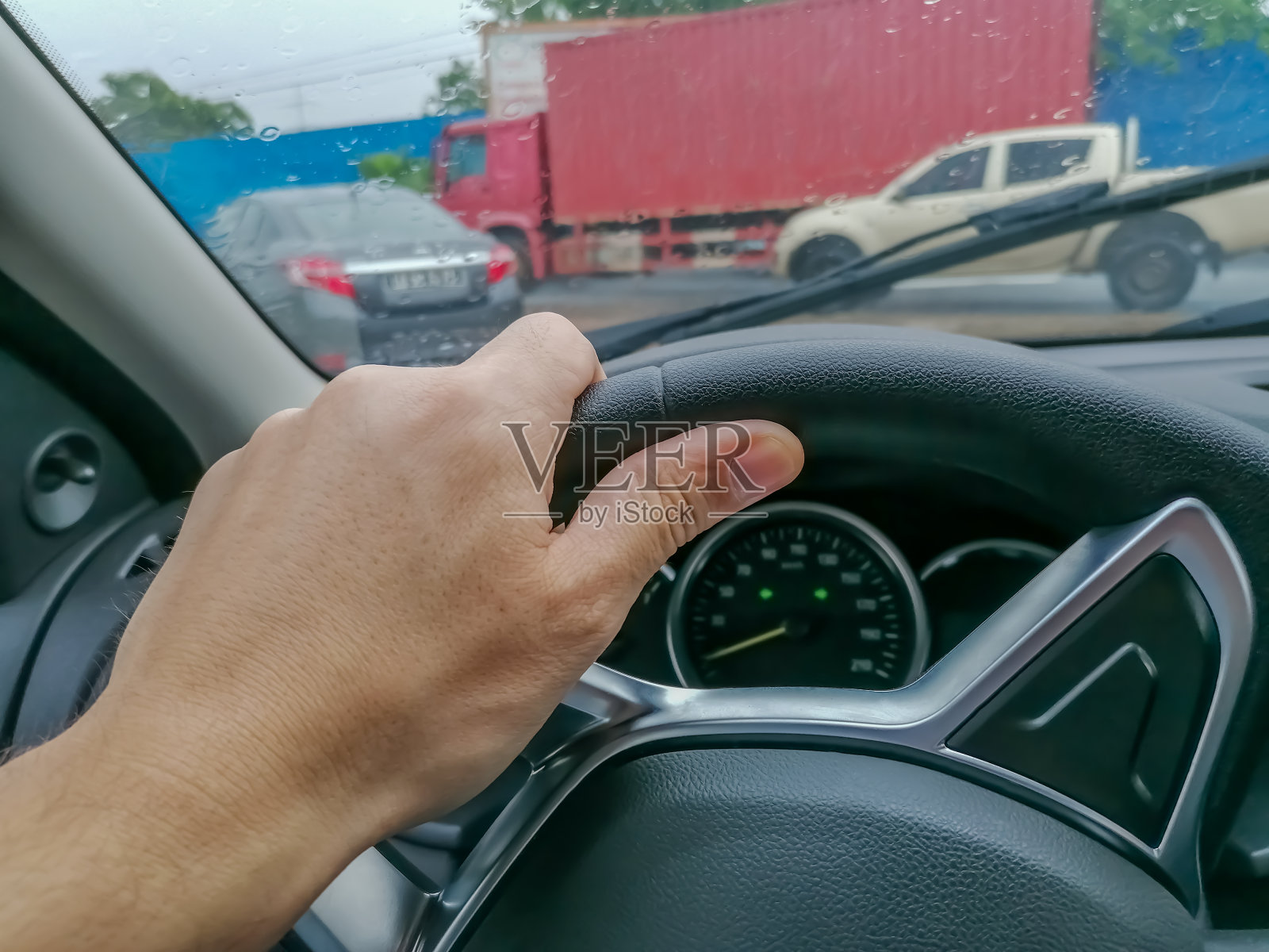 人的手驾驶现代汽车在雨天，以其他车辆为背景的道路照片摄影图片