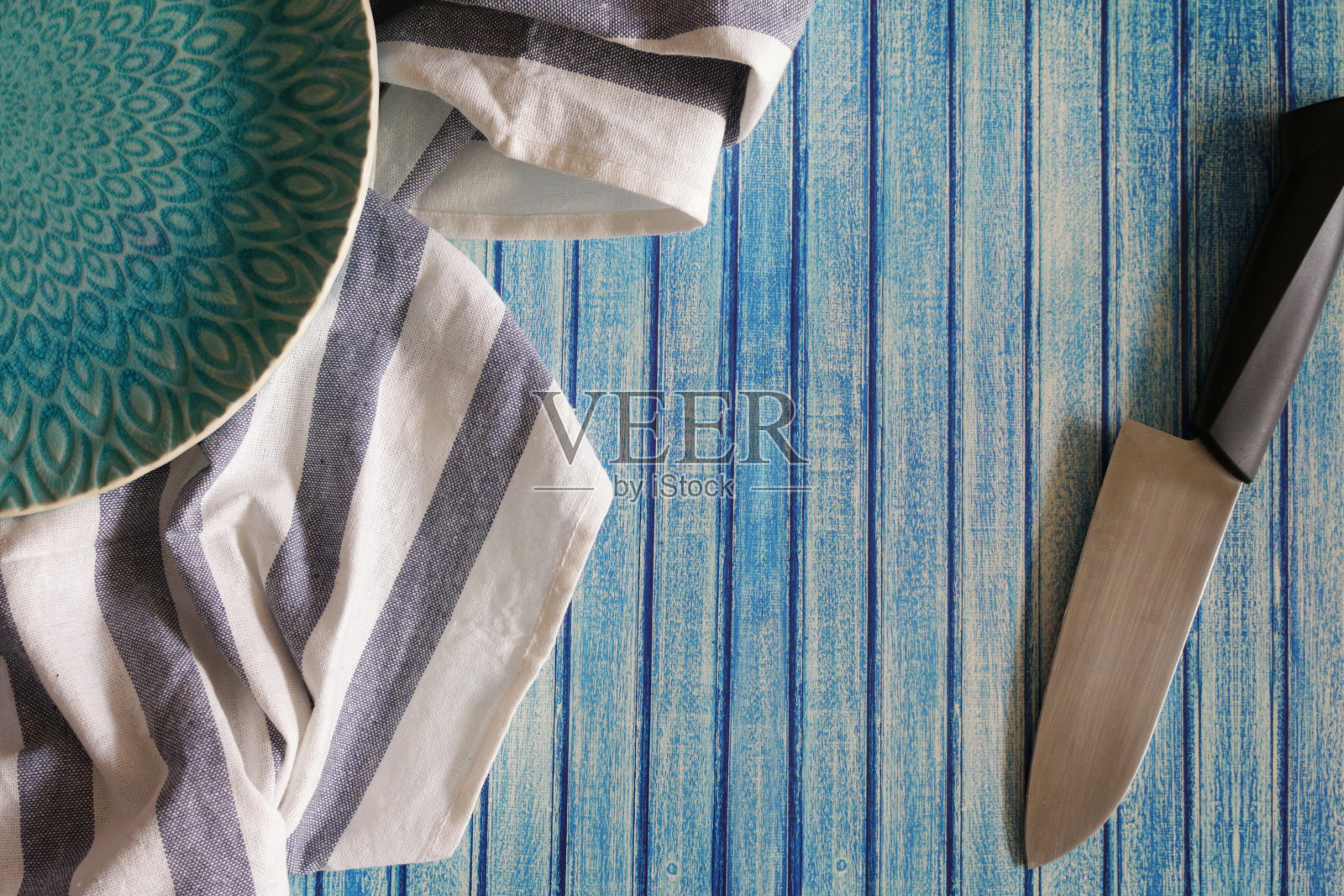 图像蓝色花纹板旁边和蓝白条纹茶巾和菜刀上的蓝色背景，蓝色舌和槽效果背景，高架视野照片摄影图片