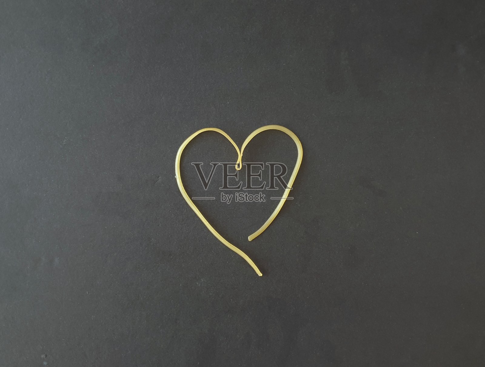 在黑色背景上画有意大利面的心。剪影的象征爱与食物。浪漫的形状面条与复制空间添加信息。极简主义的背景图像。爱创意照片摄影图片