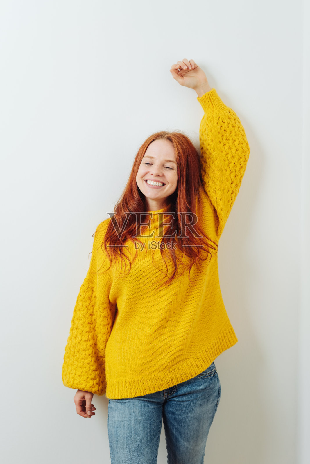 年轻活泼的红头发女人，穿着黄色毛衣照片摄影图片