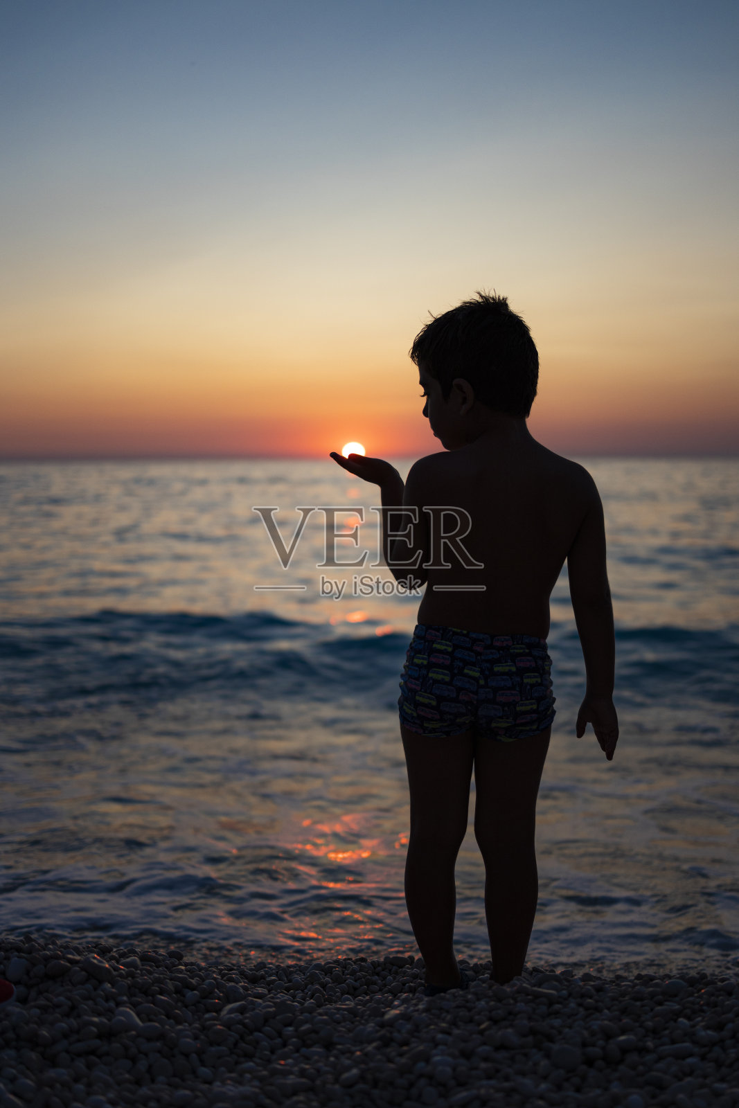 日落时分，孩子们在海滩上与太阳玩耍照片摄影图片