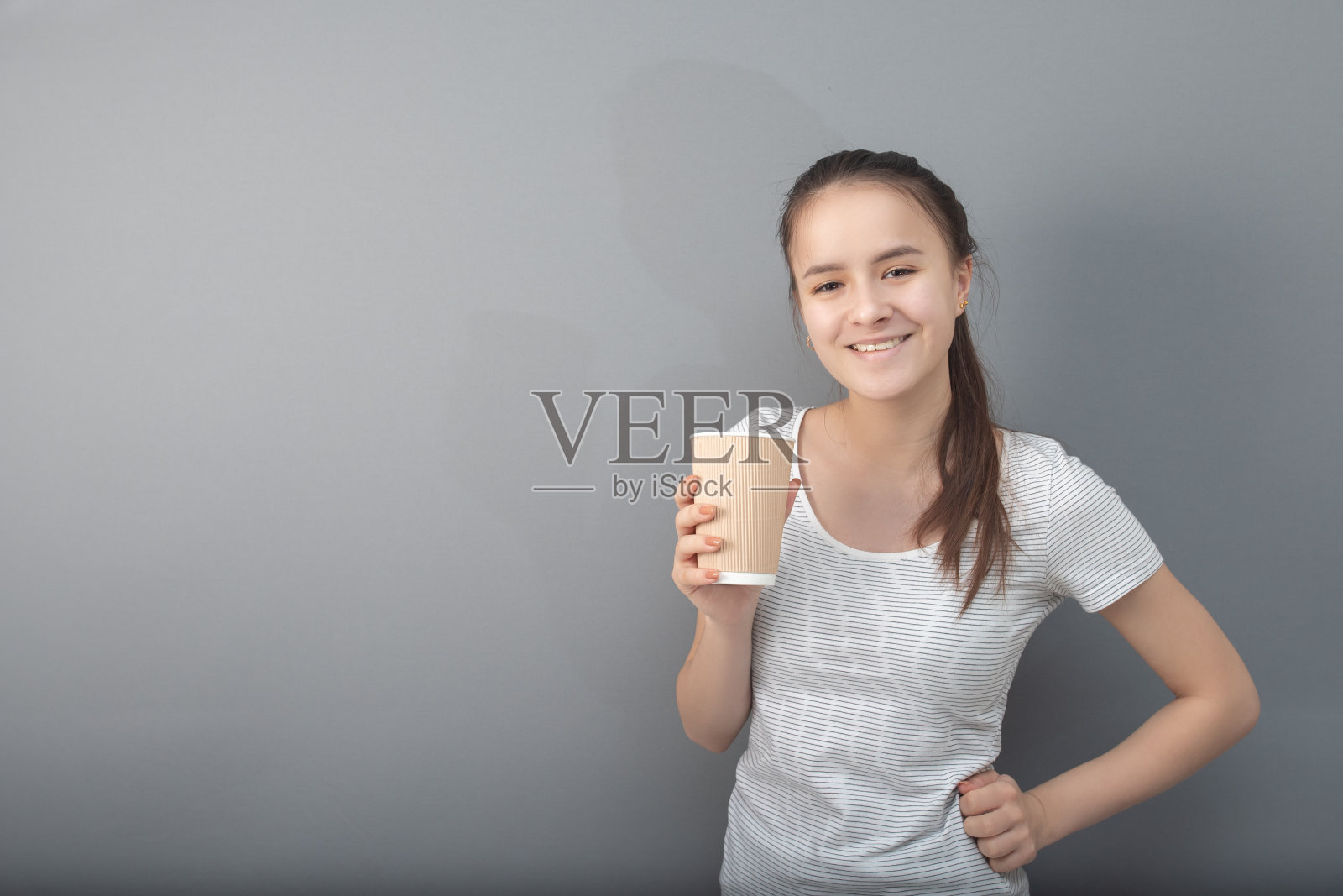 一杯芳香的咖啡。年轻女子在灰色背景下喝热饮照片摄影图片