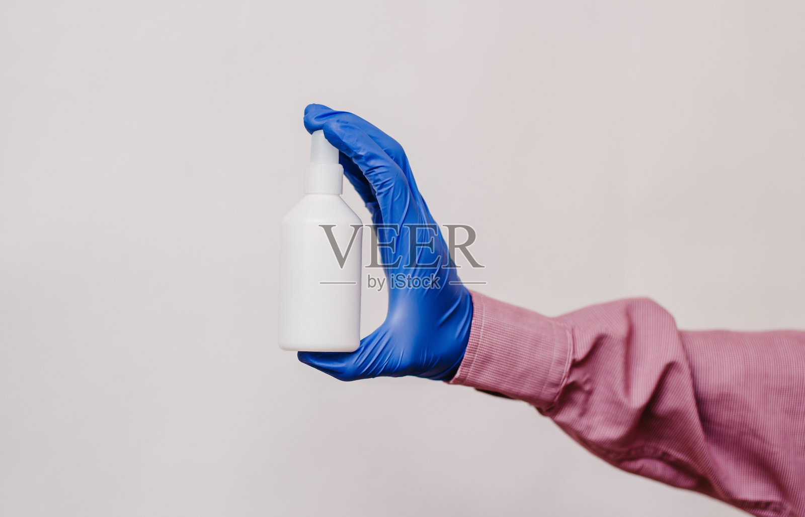 一个戴着医用手套的人拿着一个白色的瓶子。白色背景照片摄影图片