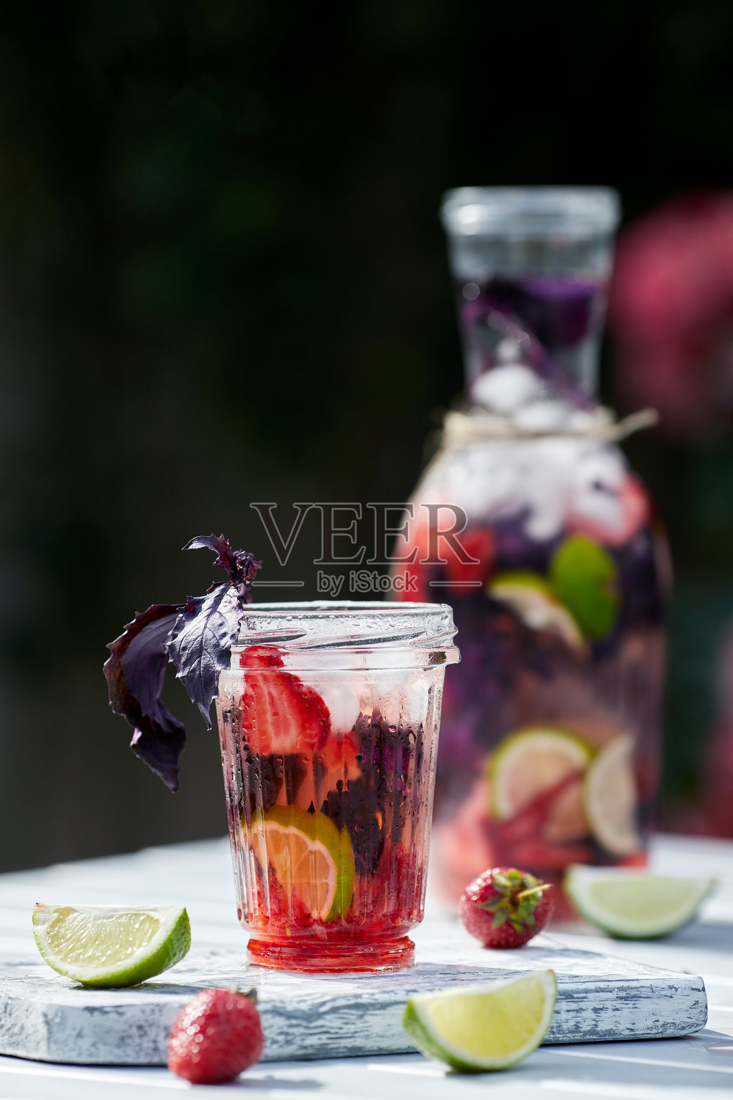 美味清爽的柠檬水，加入罗勒，酸橙和草莓。夏日饮冰。家里做的生产。照片摄影图片