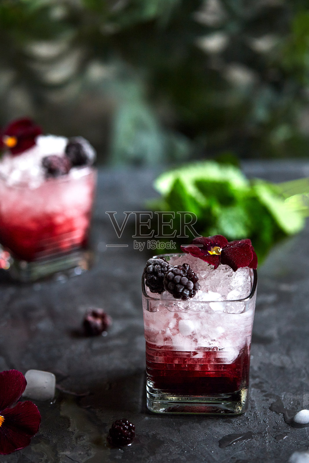 新鲜的夏季饮料。以杜松子酒、黑莓和薄荷为原料制成的美味鸡尾酒。装饰用花，三色堇照片摄影图片