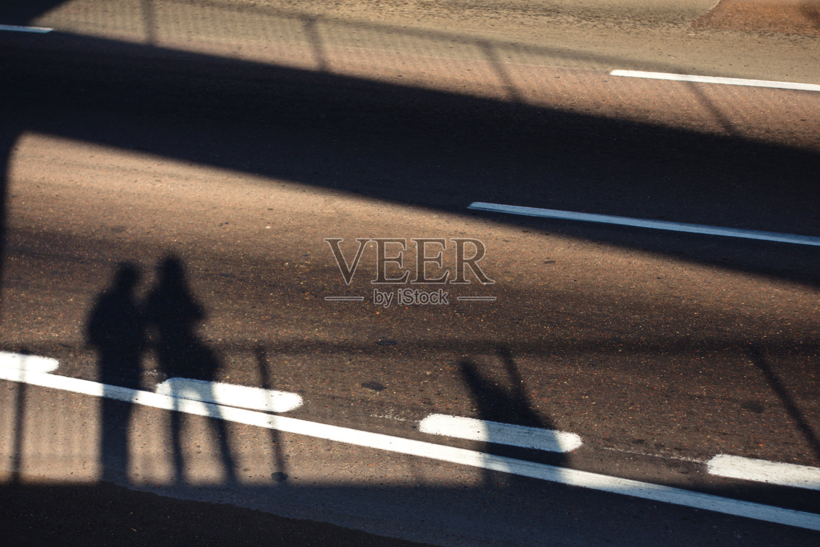 高架行人通道上的人影投射在下面空荡荡的街道上。照片摄影图片