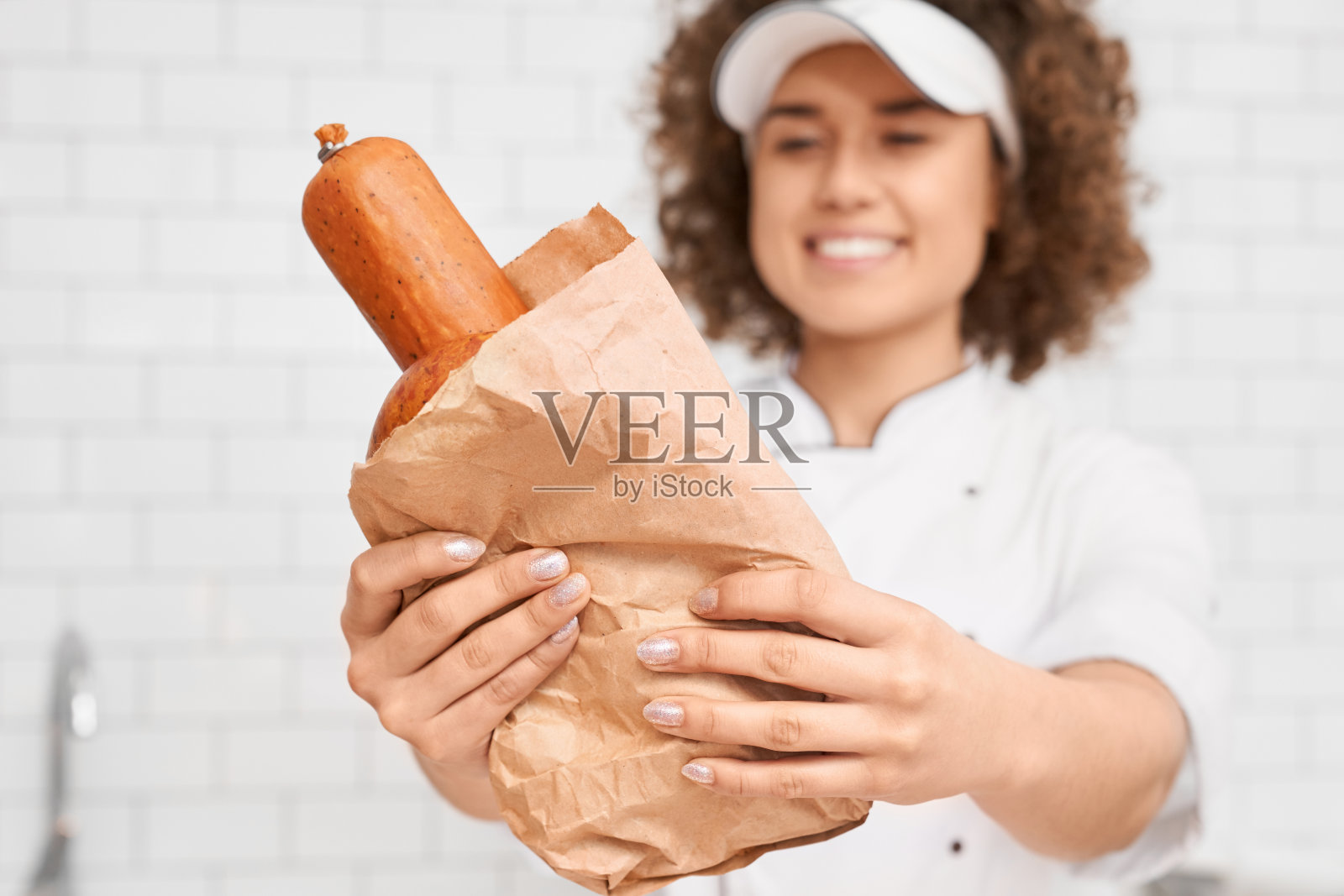 女屠夫从柜台给香肠。照片摄影图片