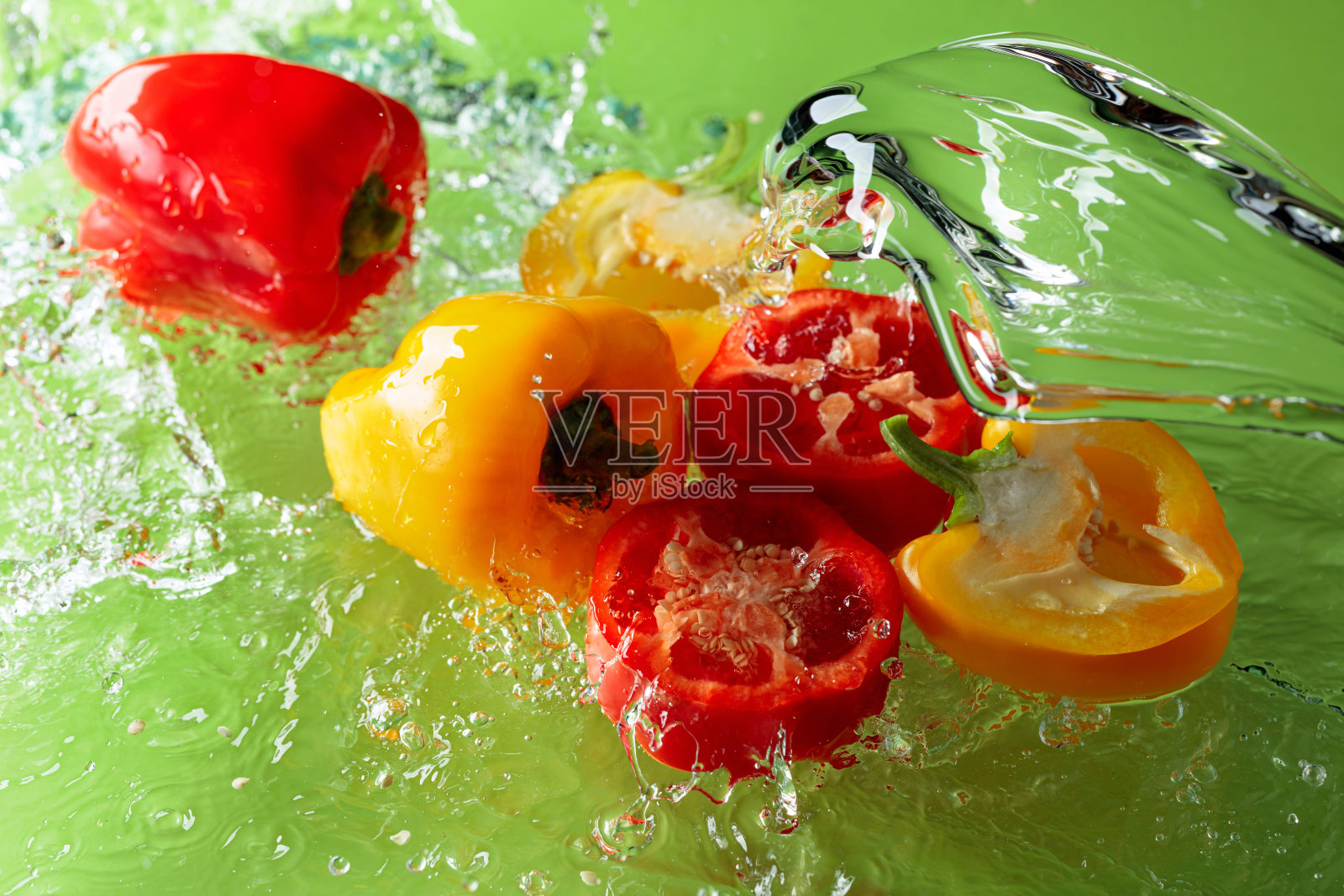 红色和黄色的辣椒在水中飞溅。照片摄影图片